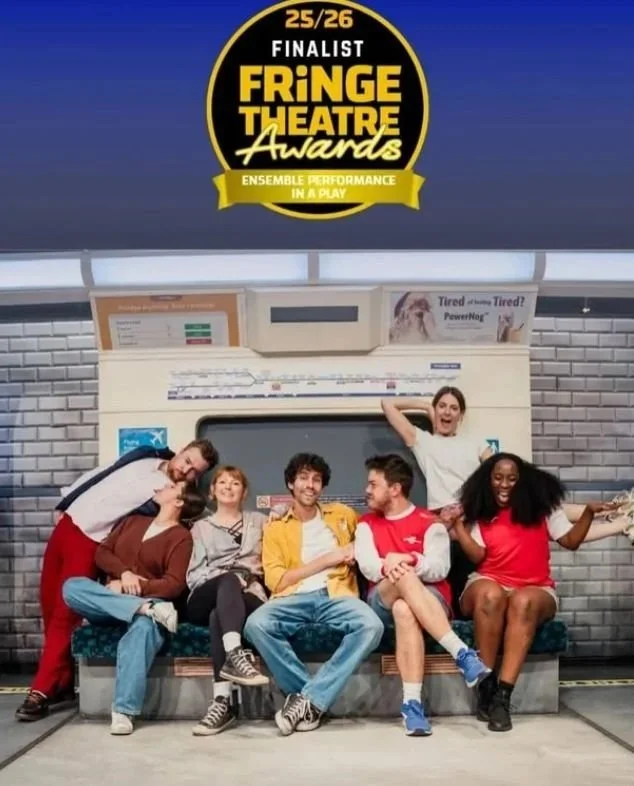 Group of six diverse young adults sitting and standing on a subway bench inside a subway station, smiling and posing for a photo with a sign above indicating they are finalists for the Fringe Theatre Awards.