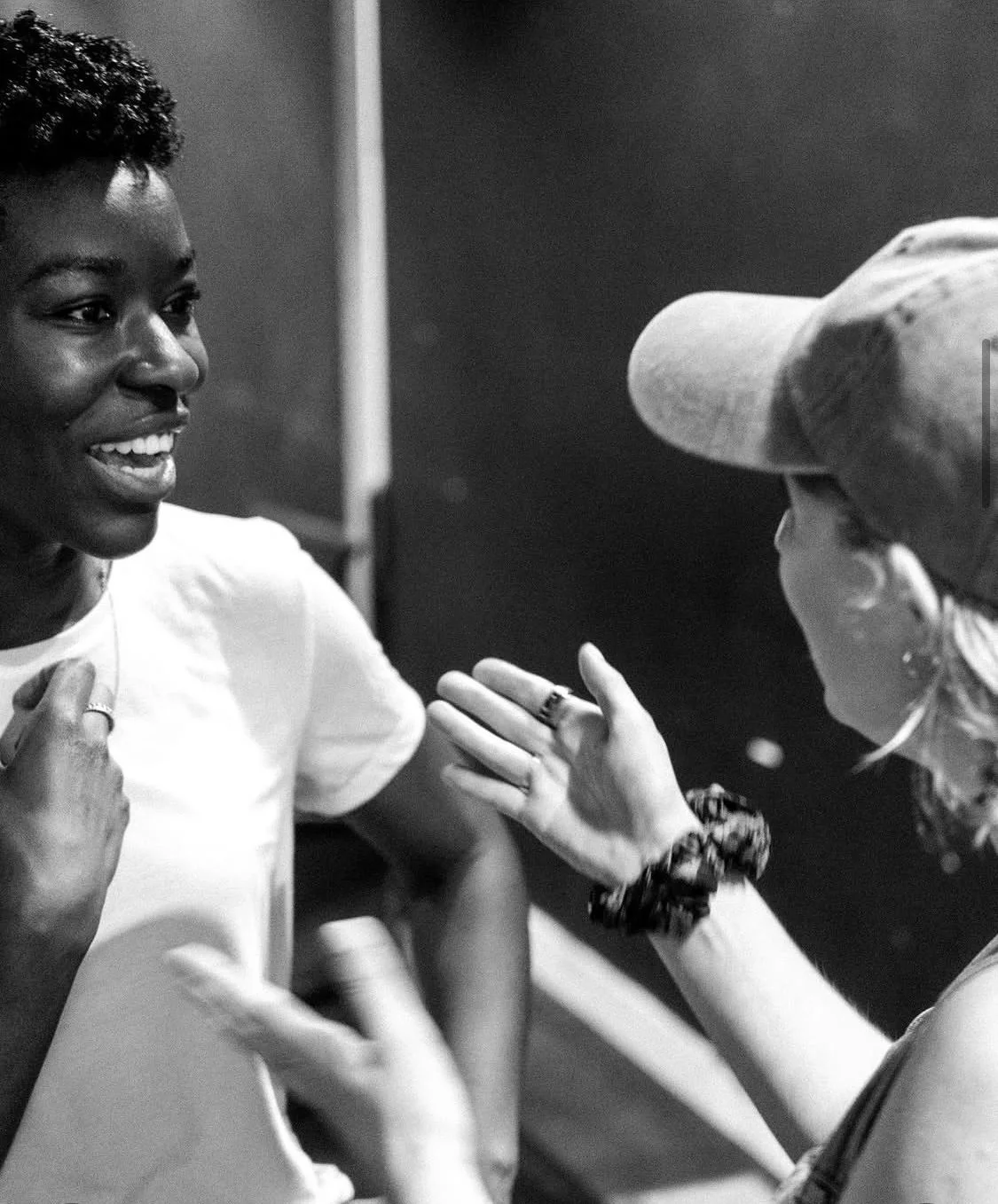 Two women talking, smiling and gesturing towards each other during a conversation.