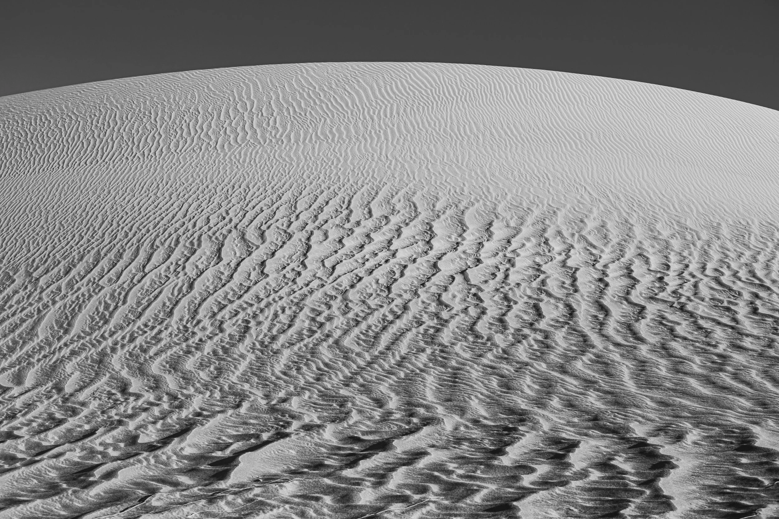 Close-up view of sand dunes with ripples and textured patterns under a dark sky.