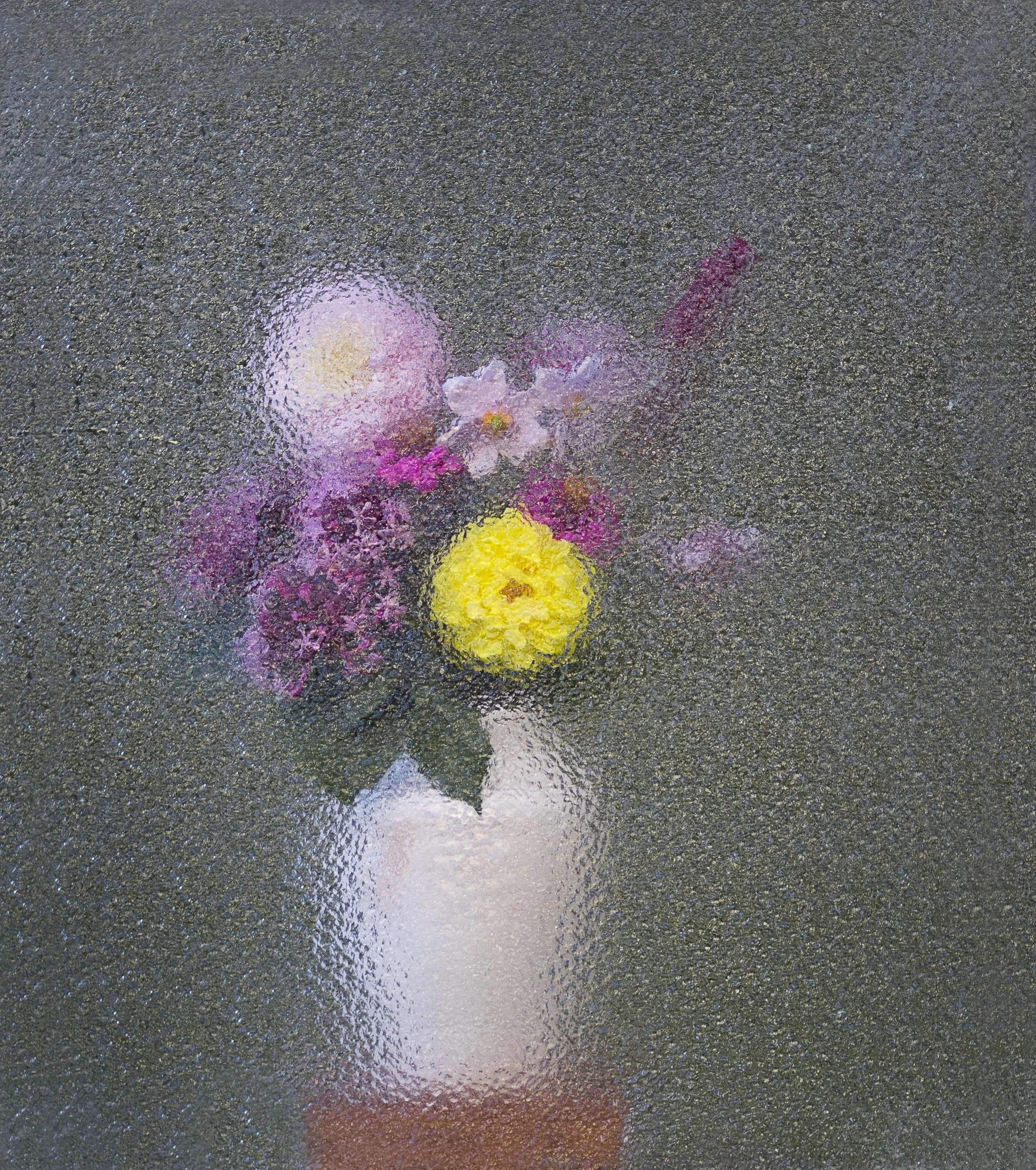 Colorful flower petals scattered on a wet asphalt surface, with reflections creating a blurred, shiny effect.