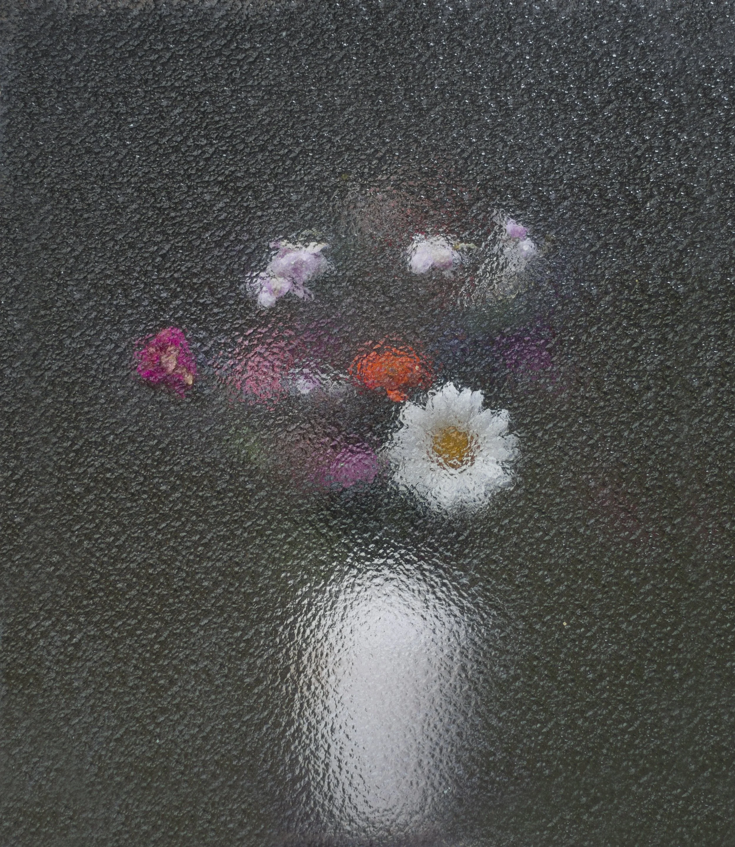 Rain-soaked asphalt road with various colorful flowers scattered on the surface.