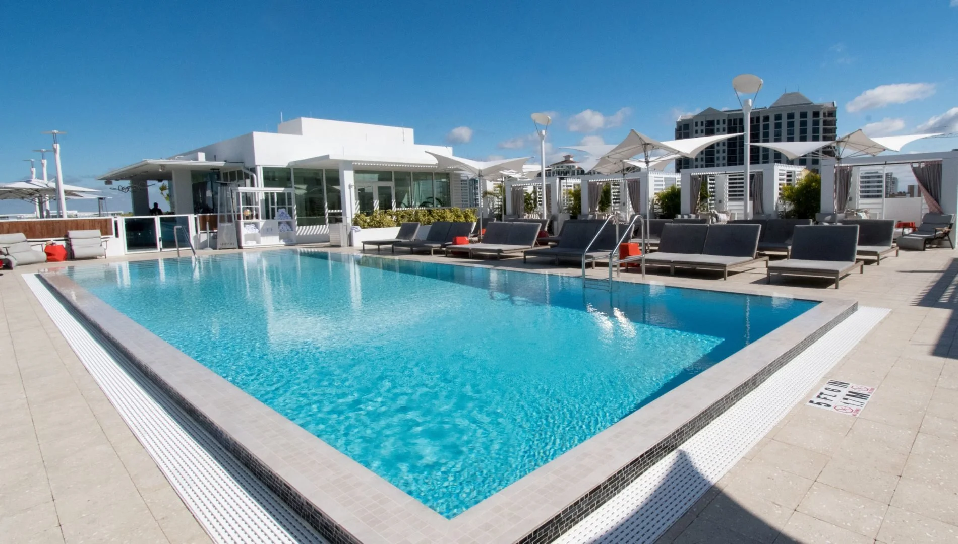Sarasota Motor Club - premium car service sarasota - Rooftop swimming pool with lounge chairs and umbrellas under a blue sky