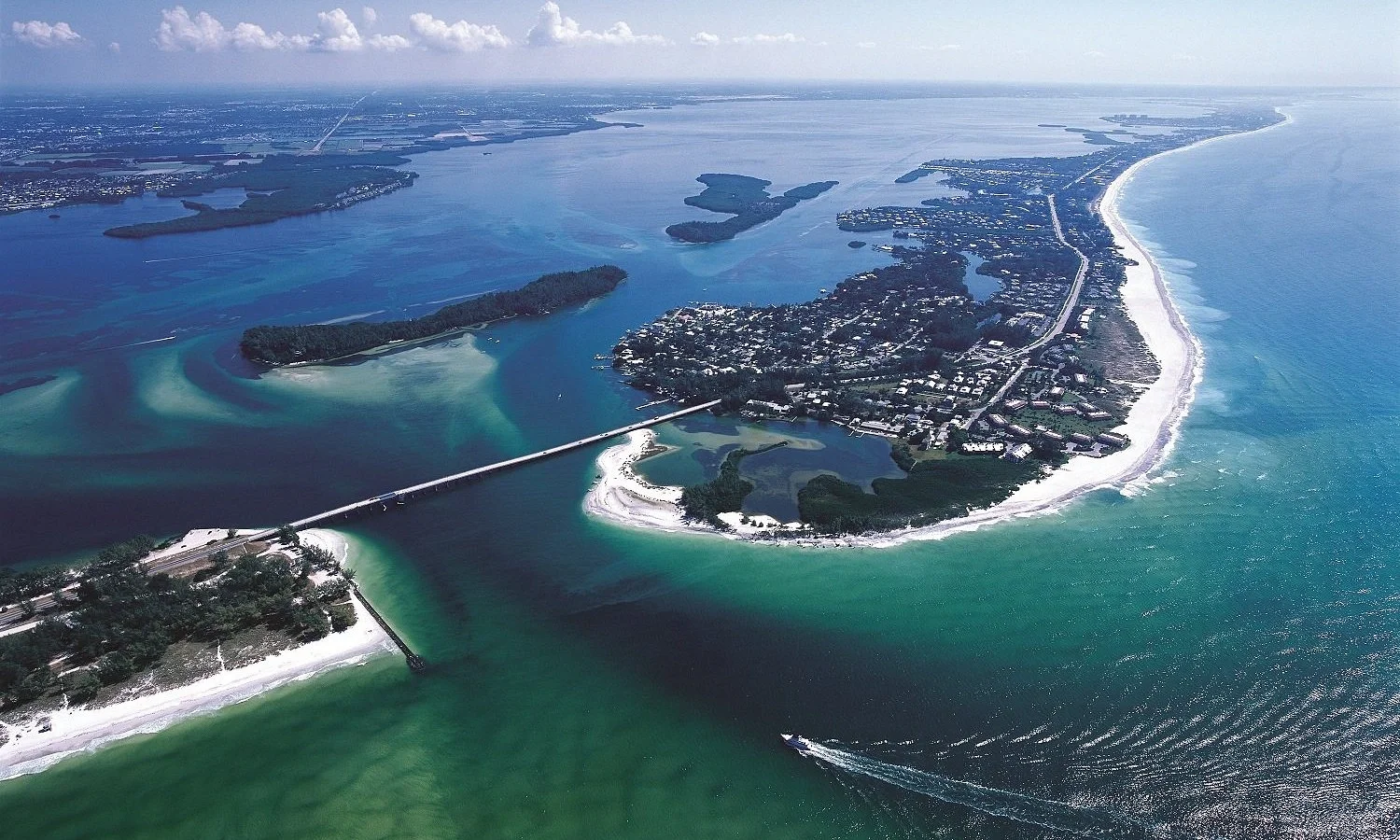Sarasota Motor Club - Exotic Car Rental Sarasota Florida - Aerial view of a coastal area with islands, bridges, beaches, and a mainland town near the ocean.