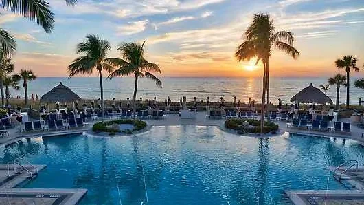 Sarasota Motor Club - Lido Beach Resort exotic car rental - Aerial view of a luxury beachfront resort with multiple swimming pools, palm trees, lounge chairs, and direct access to a sandy beach and blue ocean.