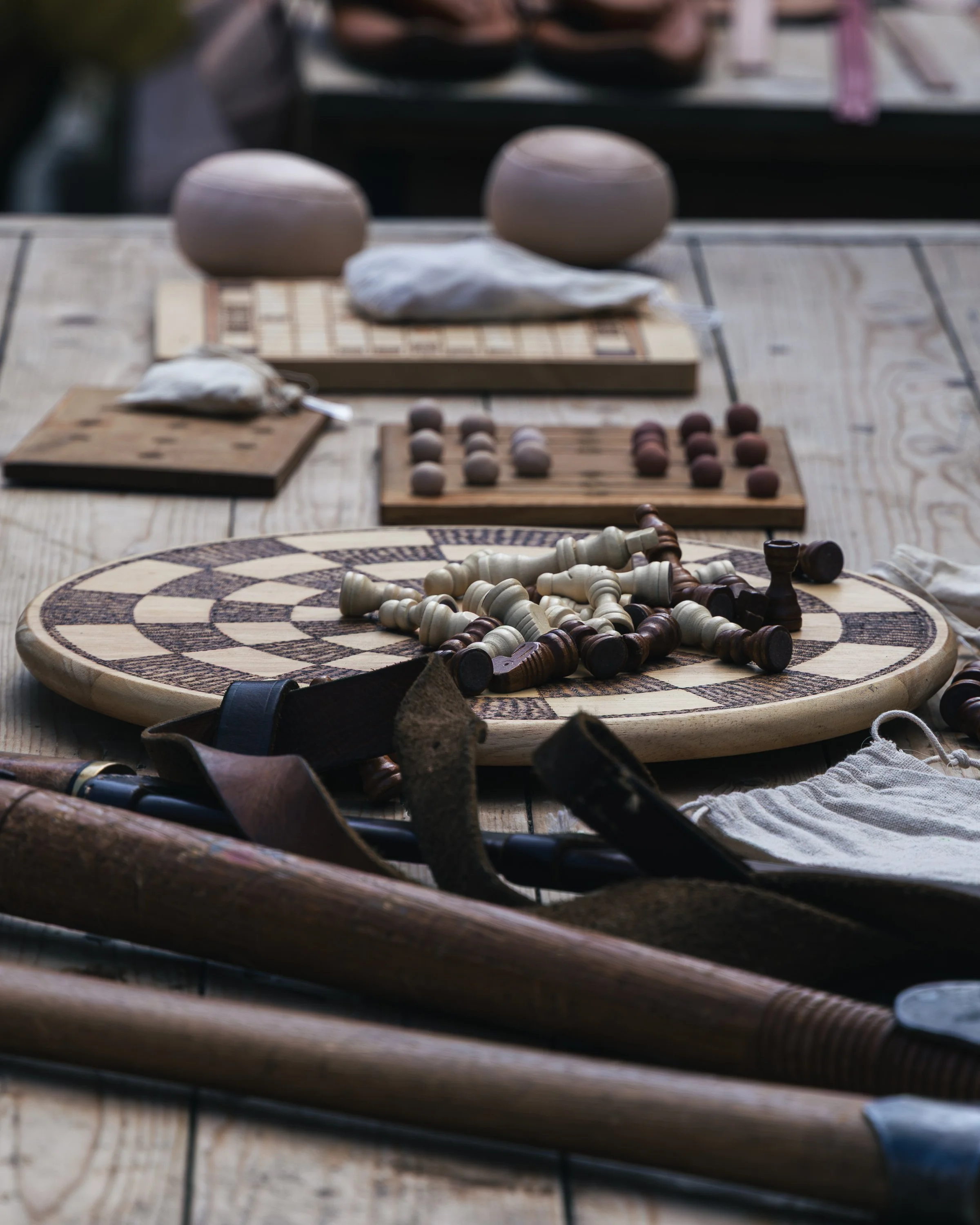 Blurred view of various chess pieces and game boards on a wooden table.