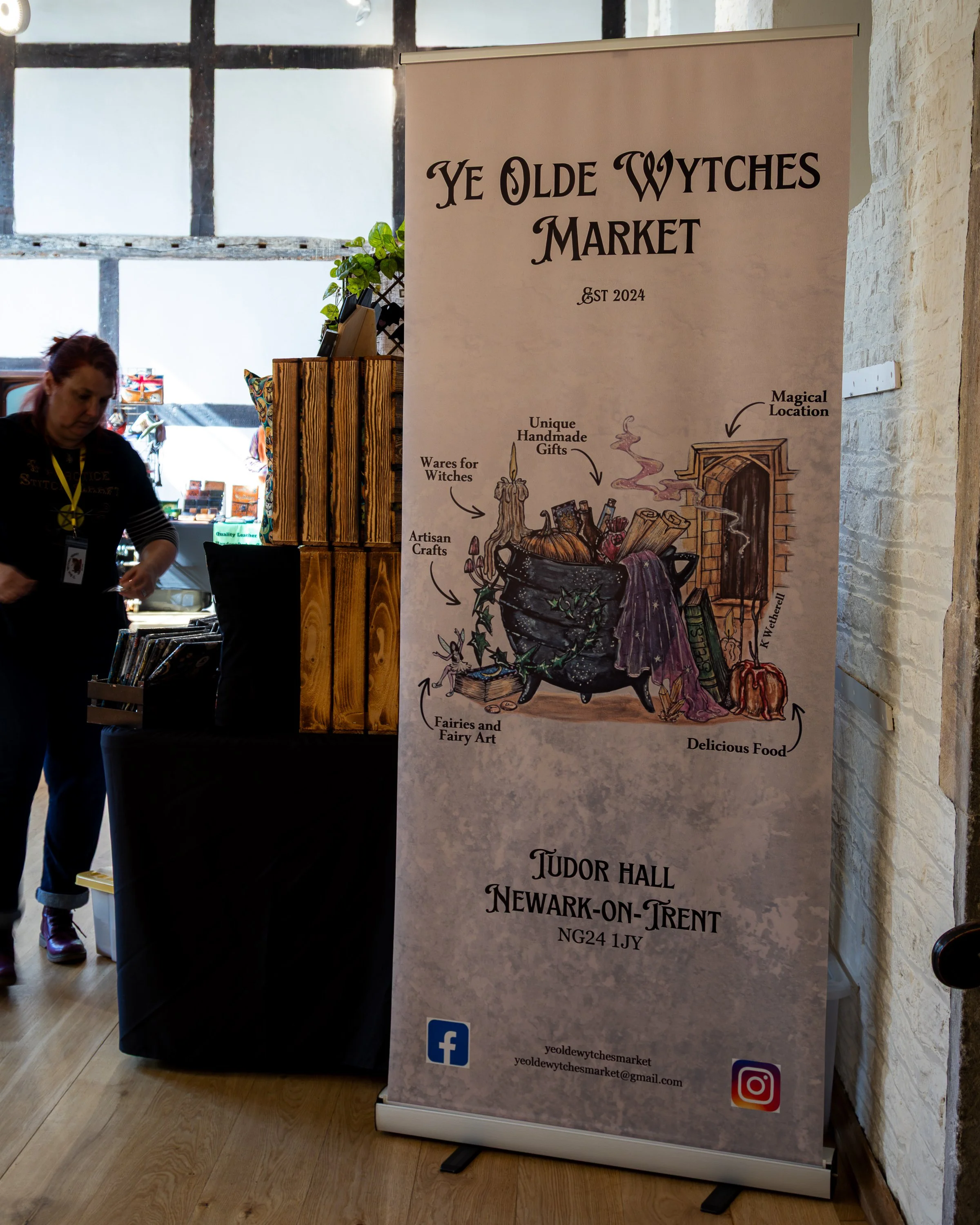 A vertical banner for Ye Olde Wytches Market at Tudor Hall, Newark-on-Trent, 2024, featuring illustrations of witchcraft items such as a cauldron with fairy art, a magic wand, a potion bottle, and a pumpkin. The banner includes contact information and social media icons for Facebook and Instagram.