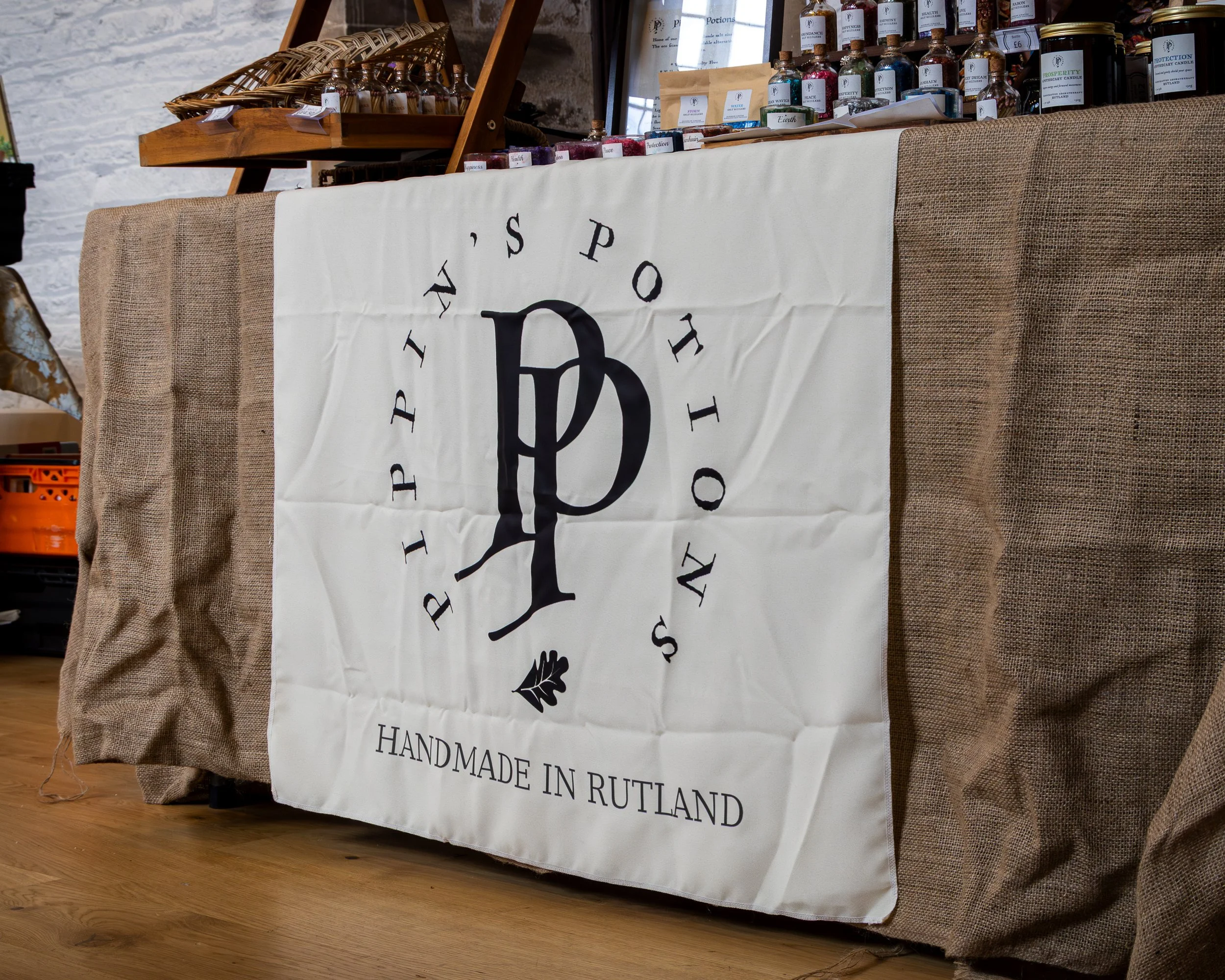 Display table with bottles and jars of handmade products in a shop, with a sign reading 'Handmade in Rutland.'