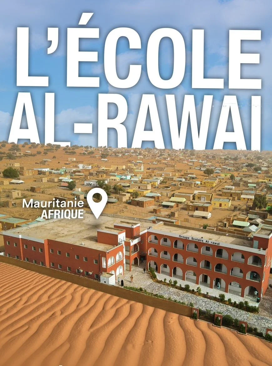 Une école à Al-Rawai au Mauretania en Afrique, située dans un environnement désertique avec des dunes de sable en premier plan, et une ville avec de nombreux bâtiments en arrière-plan.