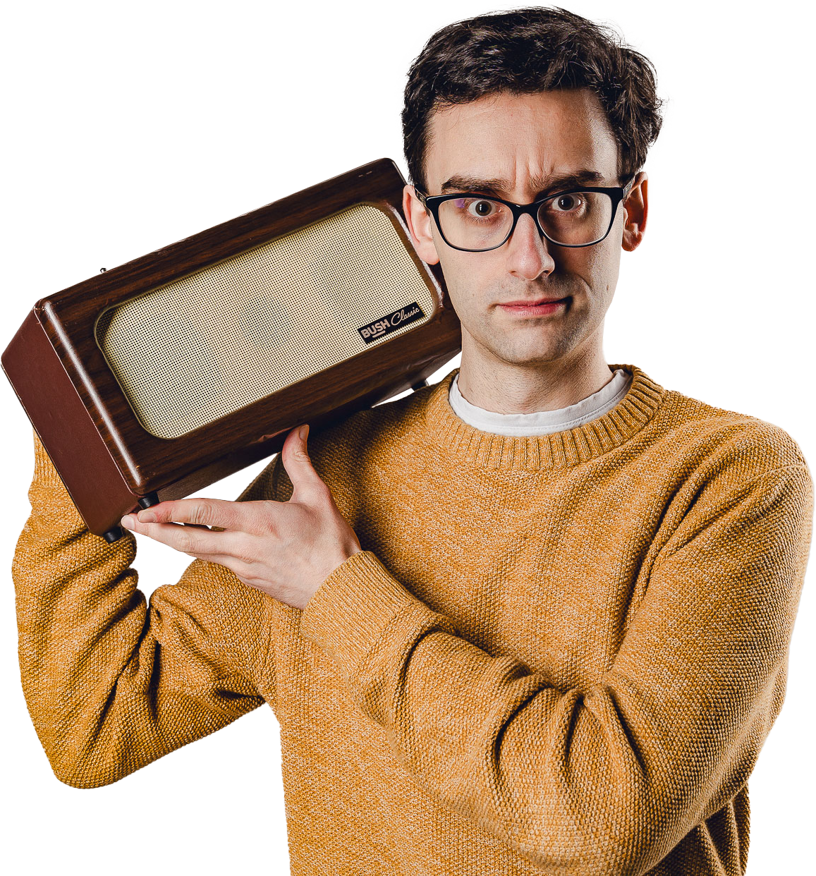 A man wearing glasses and an orange sweater holding a vintage BUSH Classic radio on his shoulder, looking at the camera with a serious expression.
