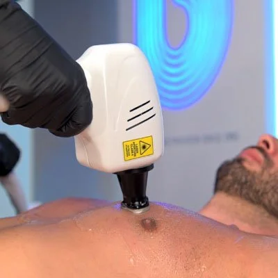 A person receiving a chest treatment with a medical device in a clinical setting.