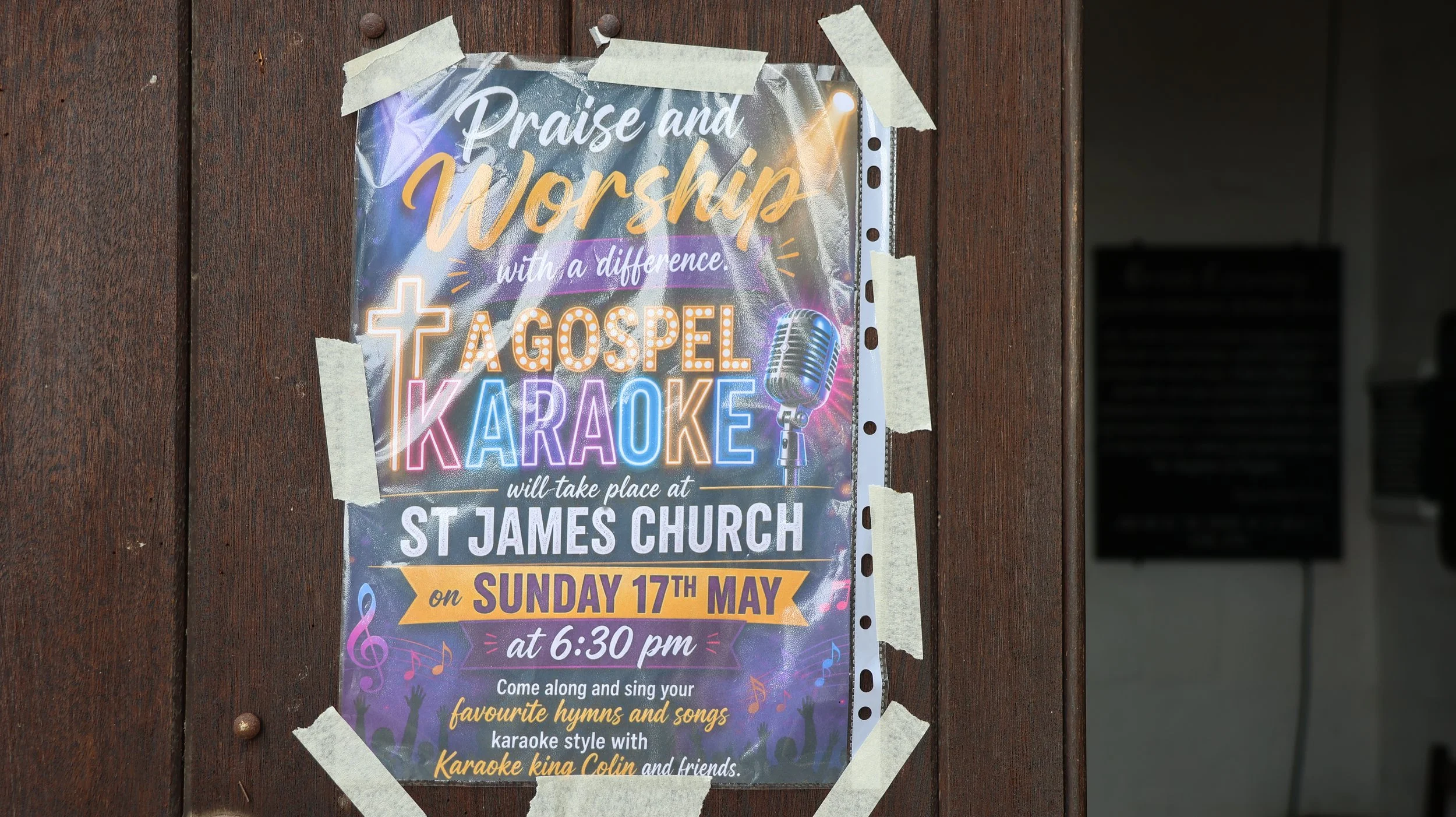 Poster taped to a wooden surface advertising a gospel karaoke event at St. James Church on Sunday, 17th May at 6:30 pm. The poster features colorful music notes and a microphone graphic.