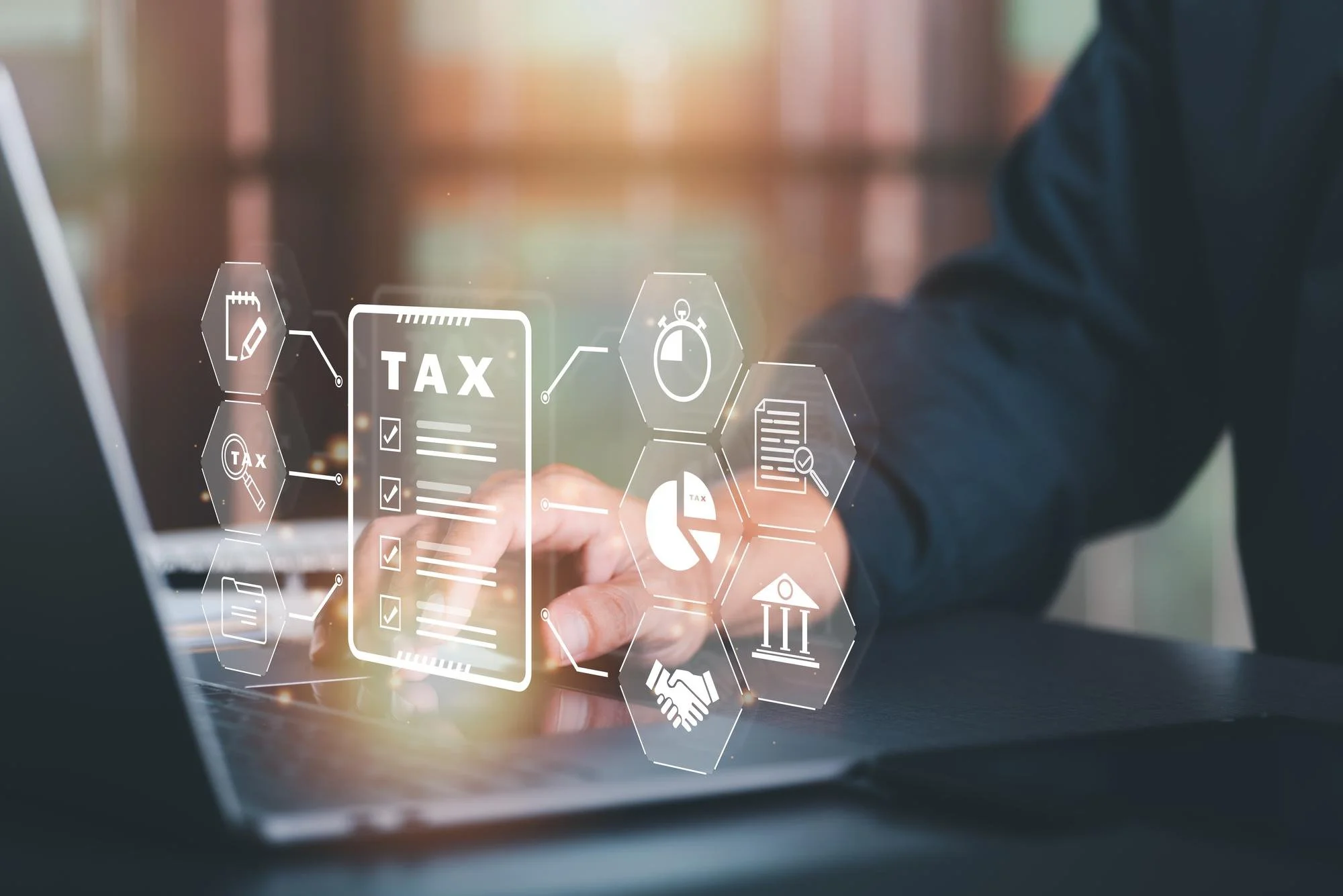 A person using a laptop with digital graphics and icons related to taxes, documents, and financial graphs overlaid.