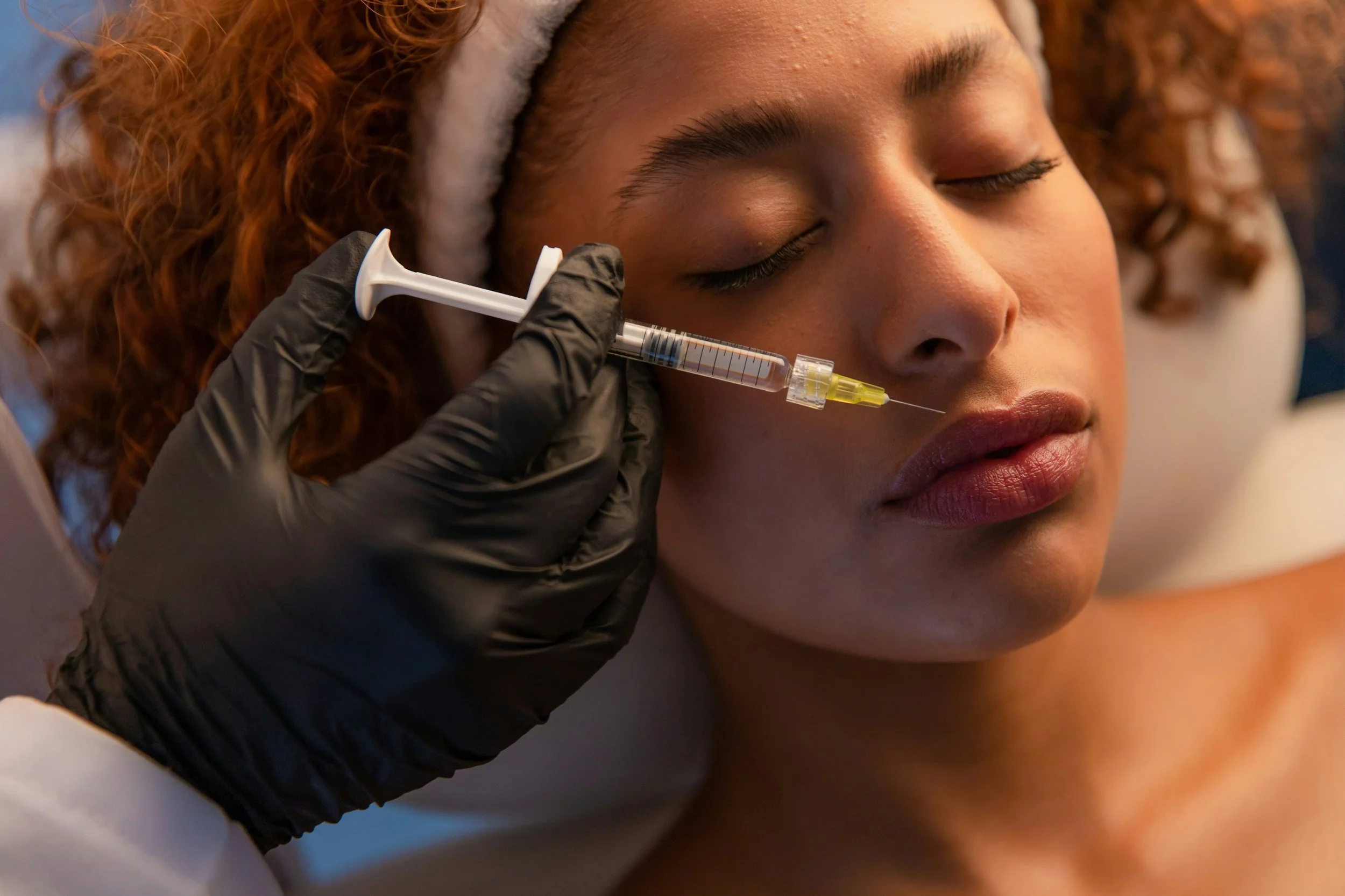 femme allongée avec une seringue qui lui injecte de l'acide hyaluronique