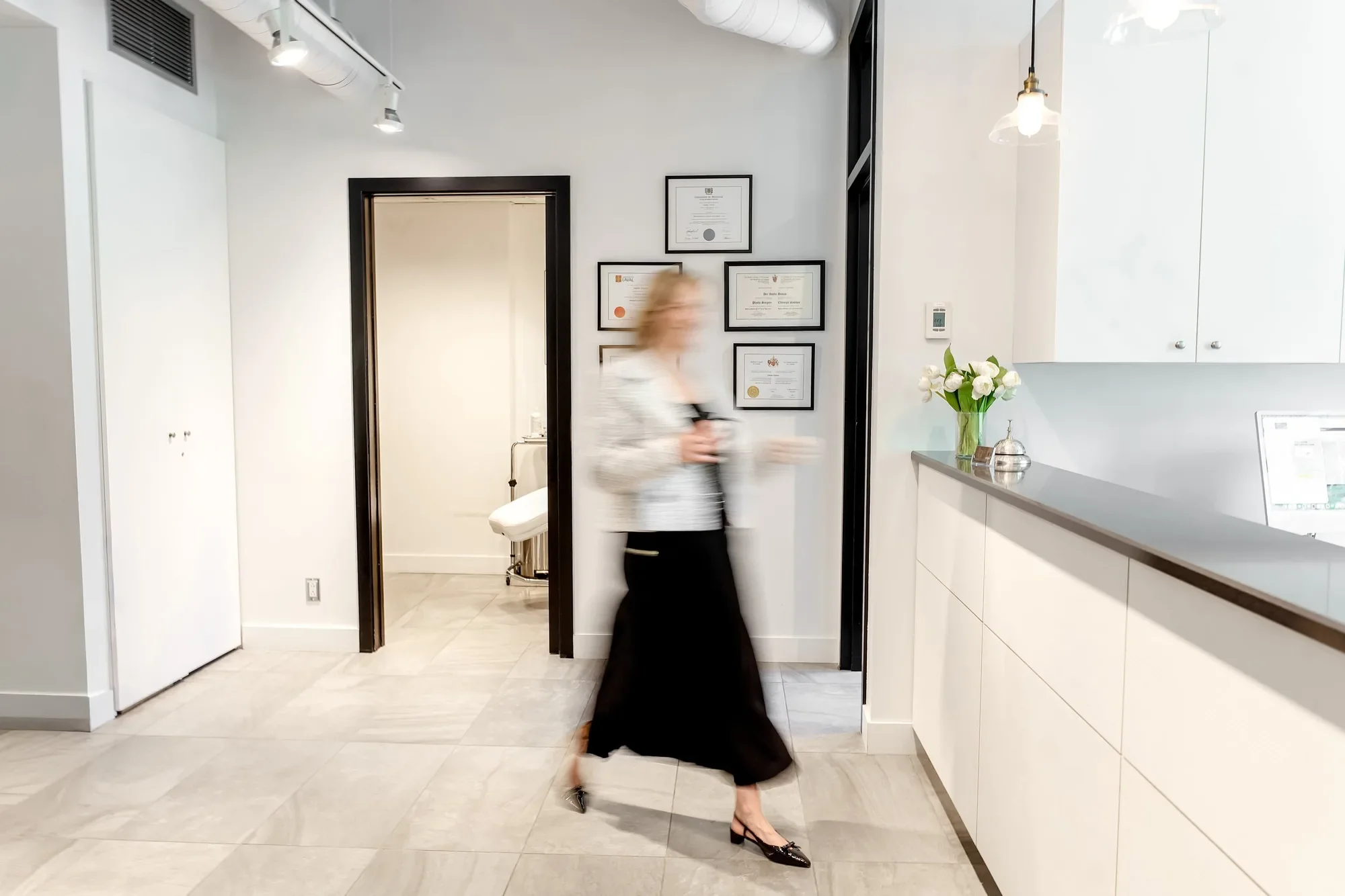 Docteure, dumas, femme blonde en robe noire qui marche dans sa clinique de chirurgie esthétique dans laquelle elle effectue de la chirurgie intime