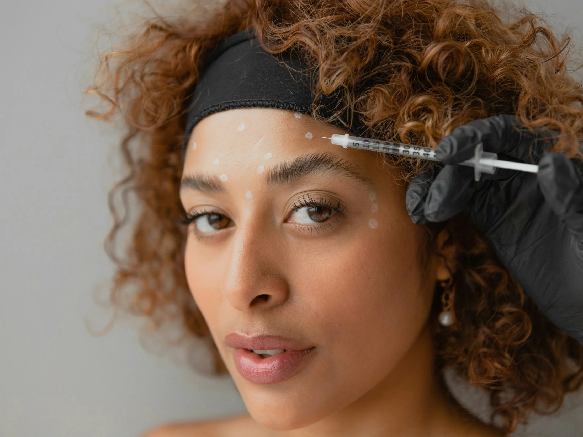 Femme qui sourit avec un font lisse après des injections de botox faites à Québec