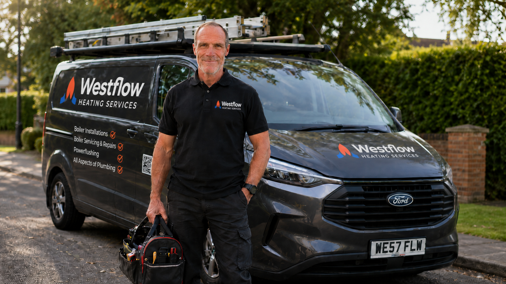 A man standing in front of a black Westflow Heating Services van, holding a tool bag, wearing a black polo shirt with the company logo, parked on a suburban street with green trees and bushes in the background.
