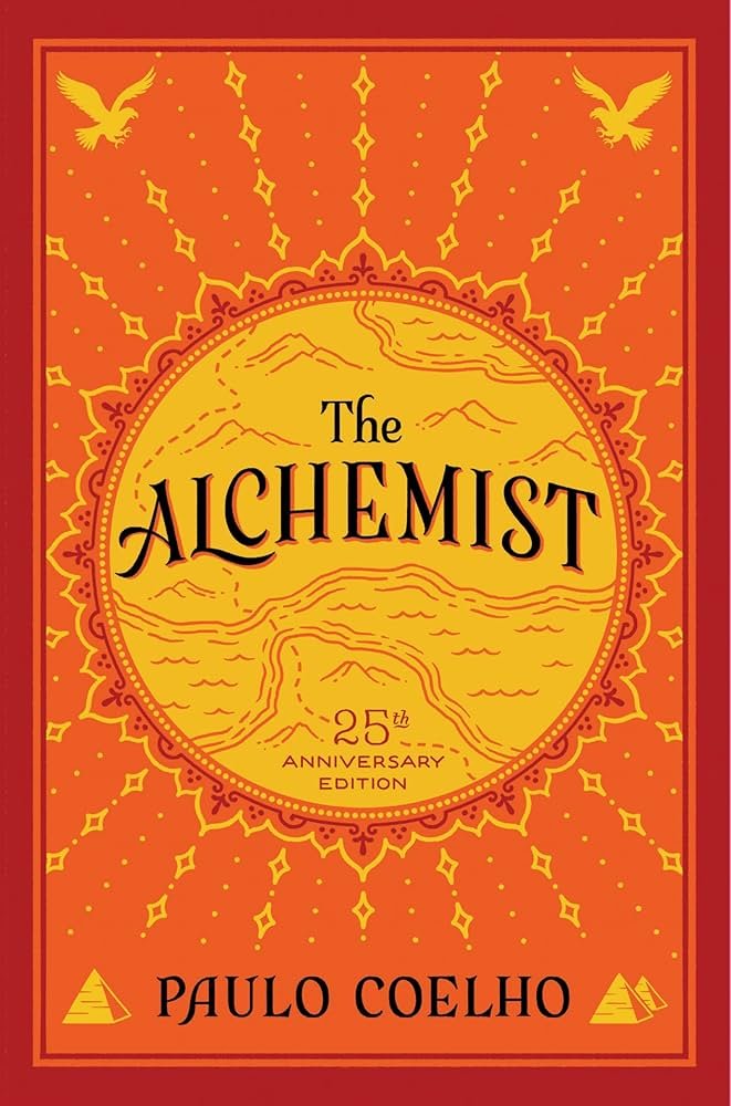 Cover of The Alchemist 25th anniversary edition by Paulo Coelho with a red and yellow color scheme, featuring a stylized sun and mountains, and two palm trees at the bottom corners.