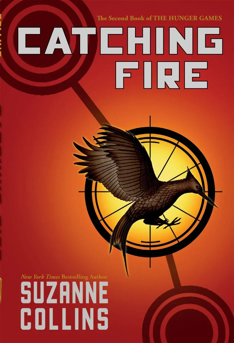 Book cover for 'Catching Fire' by Suzanne Collins, showing a hummingbird in front of a target with a red and orange background.