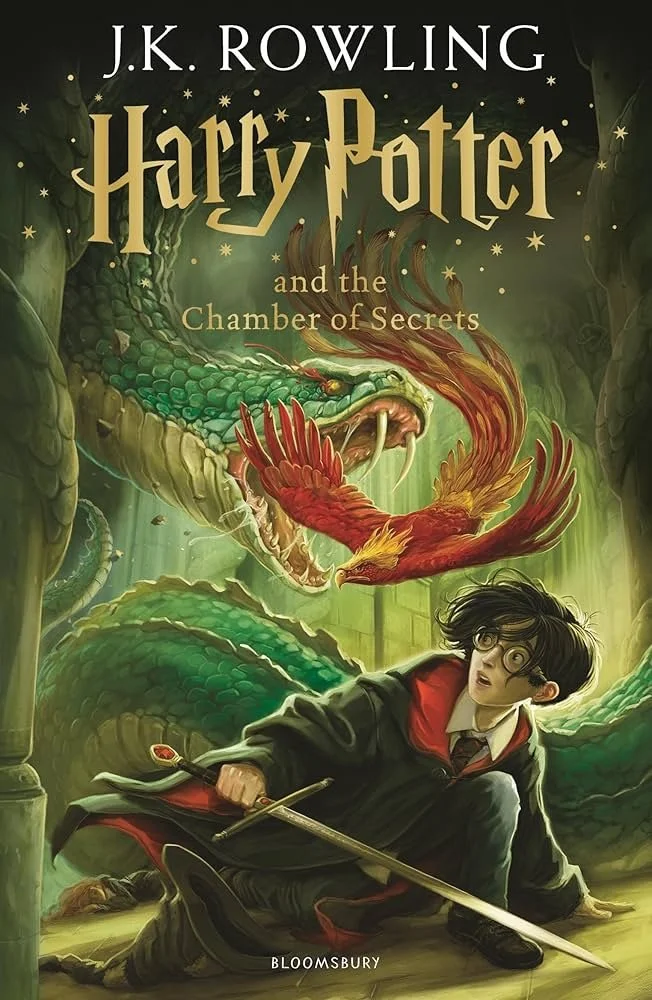 Book cover for 'Harry Potter and the Chamber of Secrets' featuring Harry Potter with glasses and a wand, looking surprised or frightened, with a large green serpent and a fiery red and yellow phoenix in the background, set in a dark, magical environment.