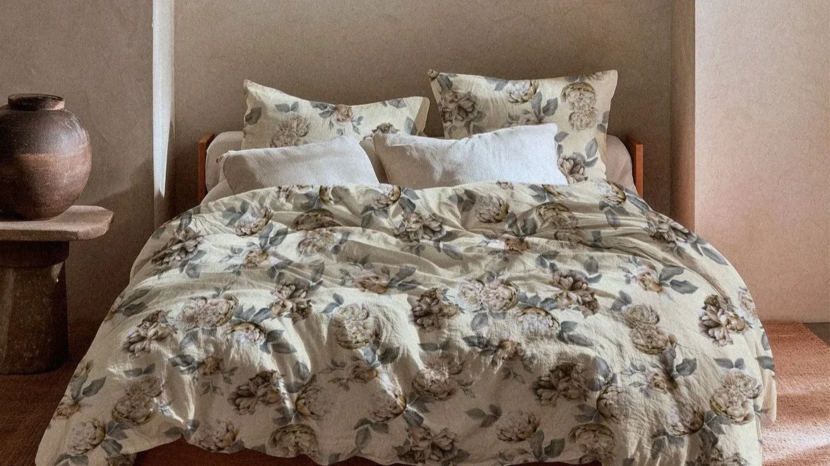 A bed with floral patterned bedding and four pillows in a cozy bedroom setting.