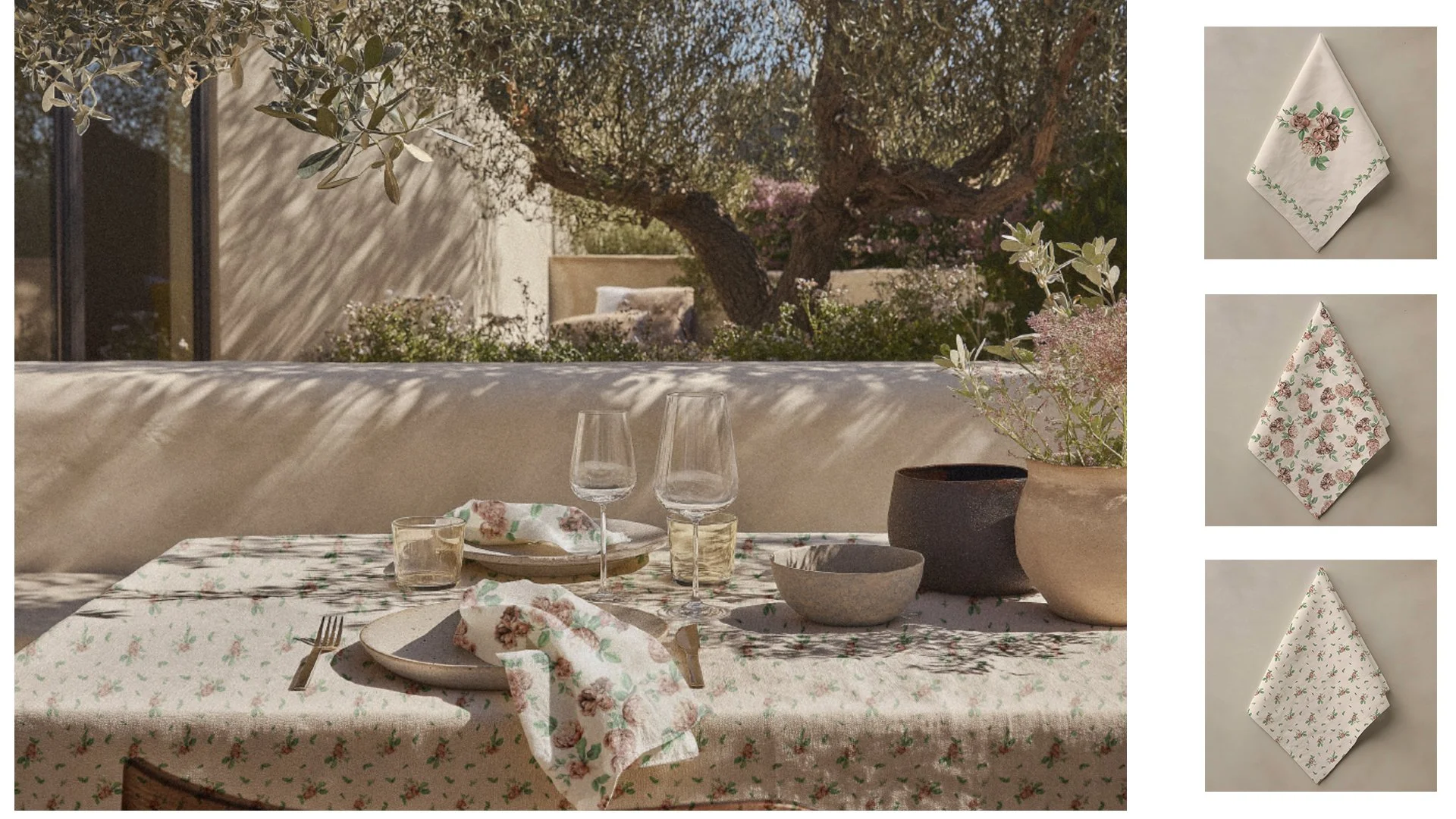 An outdoor dining setup with a floral tablecloth, two wine glasses, a small bowl, and cloth napkins on a garden table. In the background, there are potted plants and a tree, with a shaded patio area.