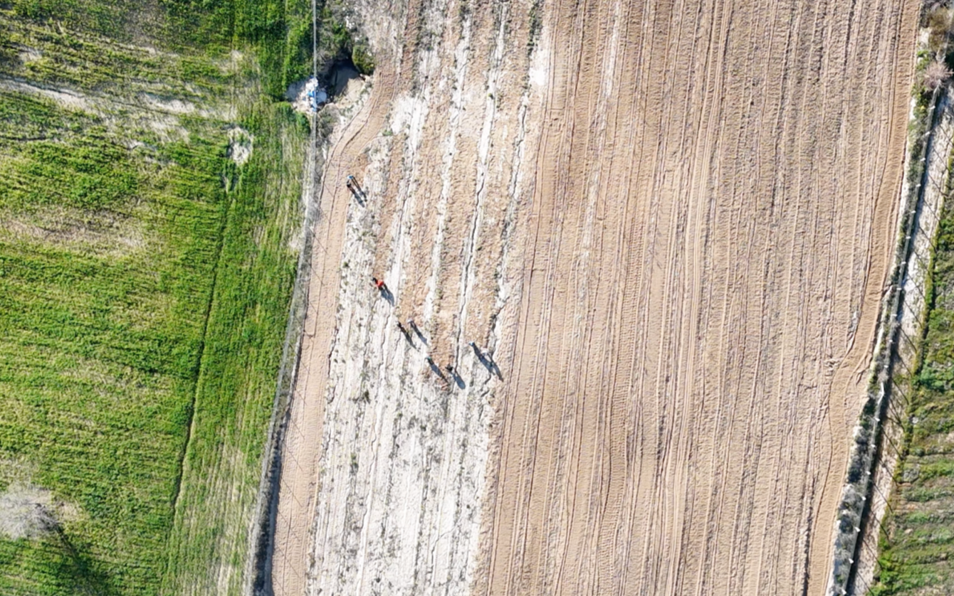 Aerial view of a farmland with two different crop fields and two people walking on a dirt path.