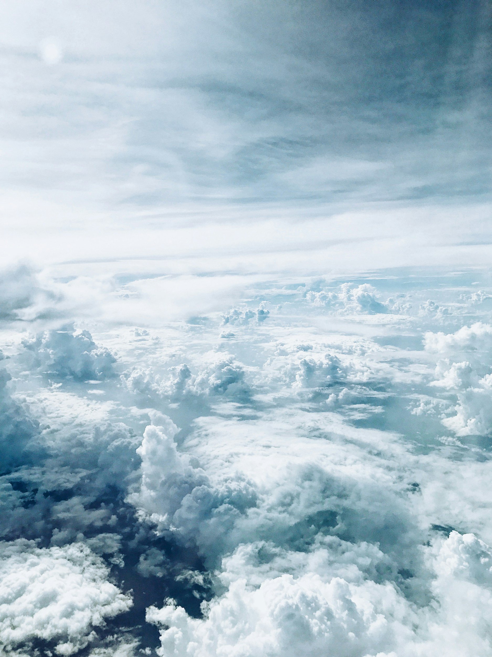 Vue aérienne de nuages blancs et bleus dans le ciel avec un Soleil visible en haut à gauche.