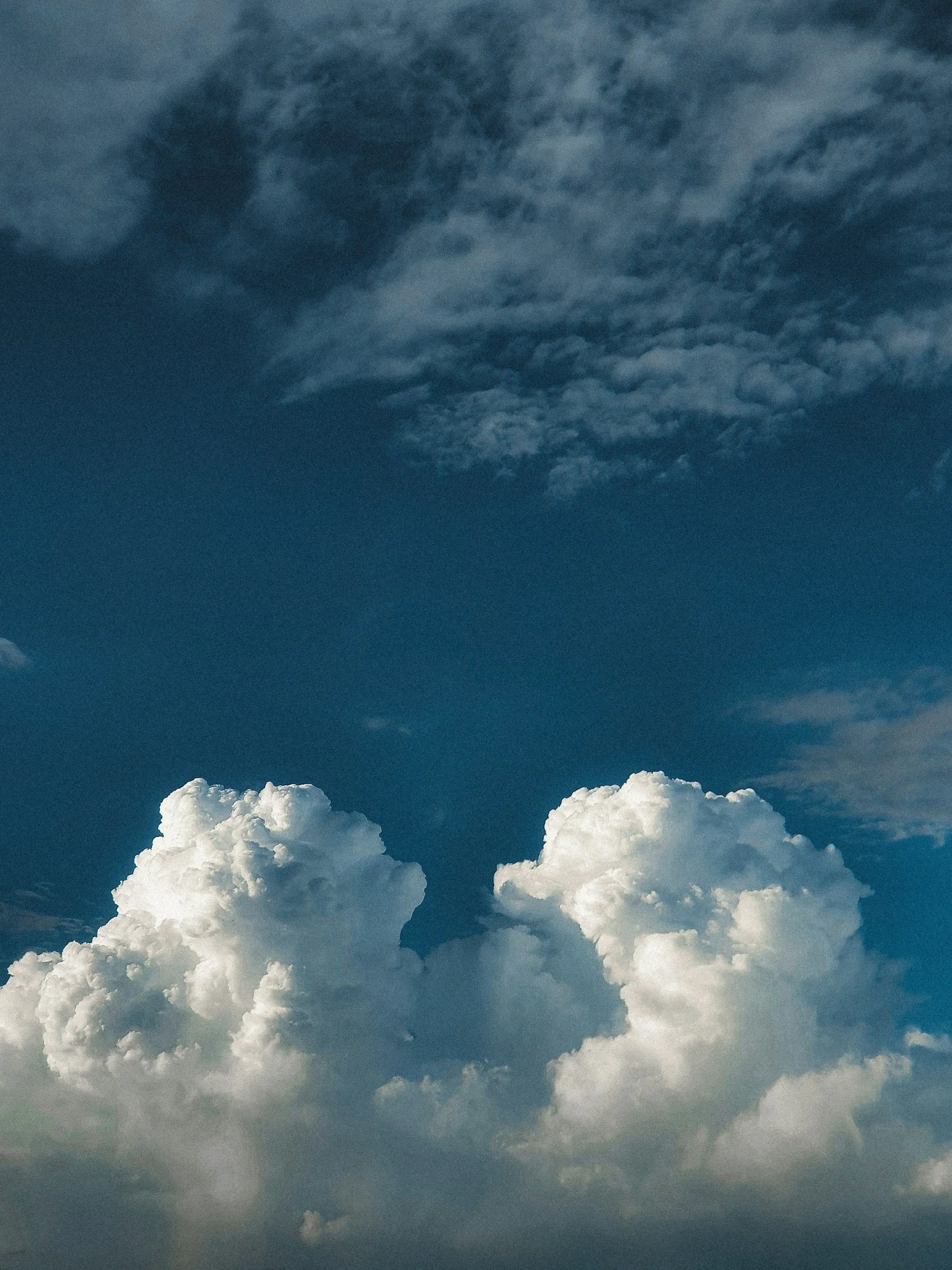 Ciel nuageux avec des nuages blancs cotonneux en bas et des nuages plus sombres en haut.
