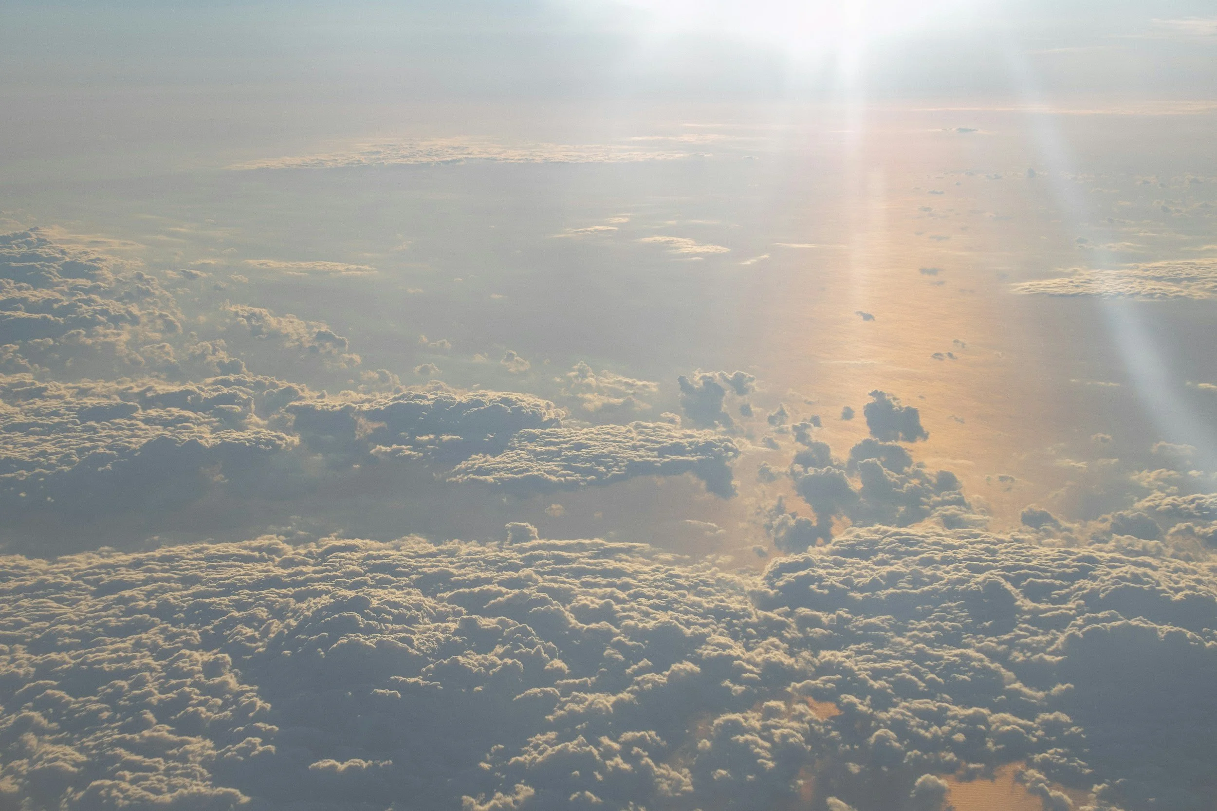 Vue aérienne des nuages au-dessus de la mer avec la lumière du soleil refletant sur l'eau.