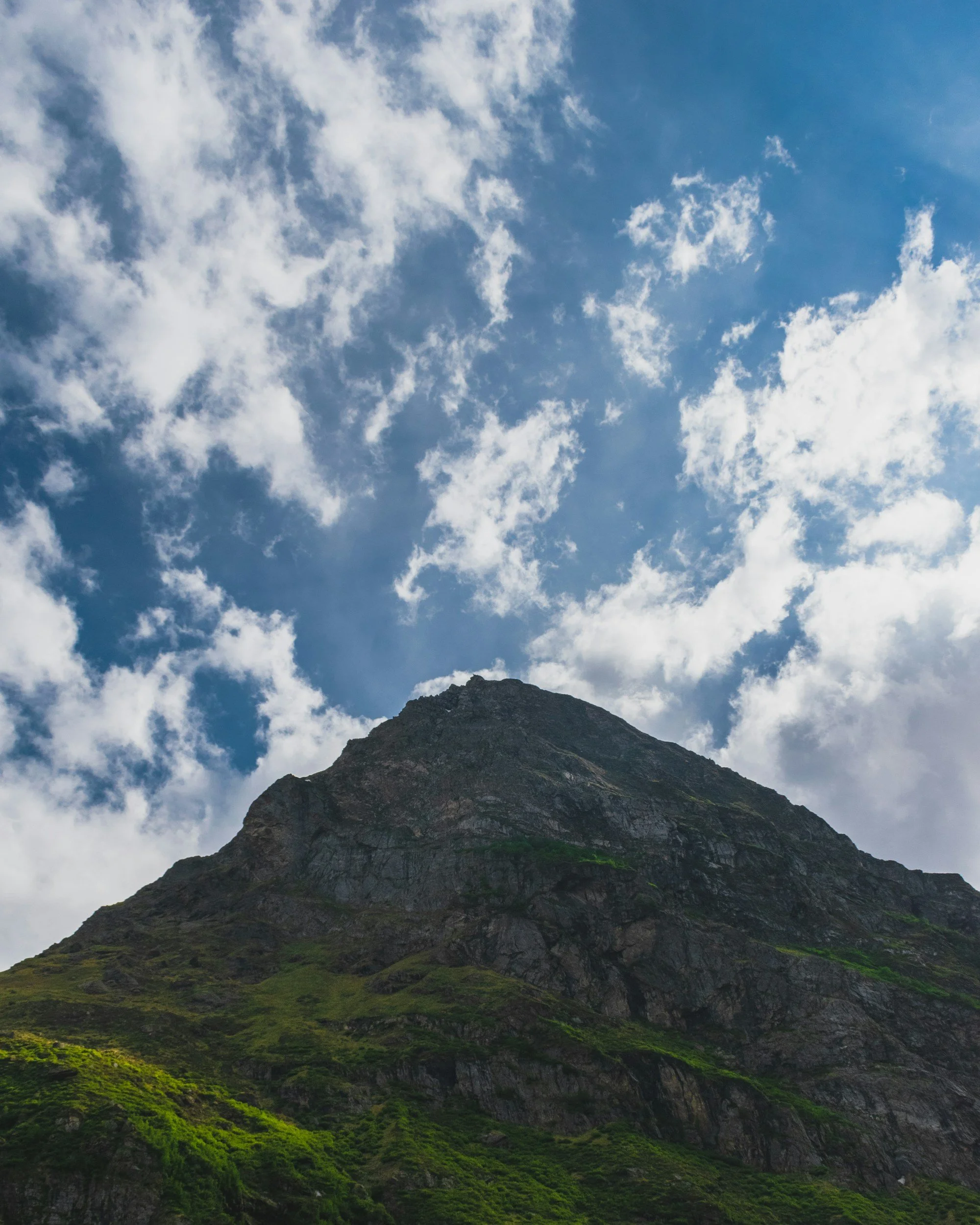 Montagne escarpée sous un ciel bleu avec nuages blancs