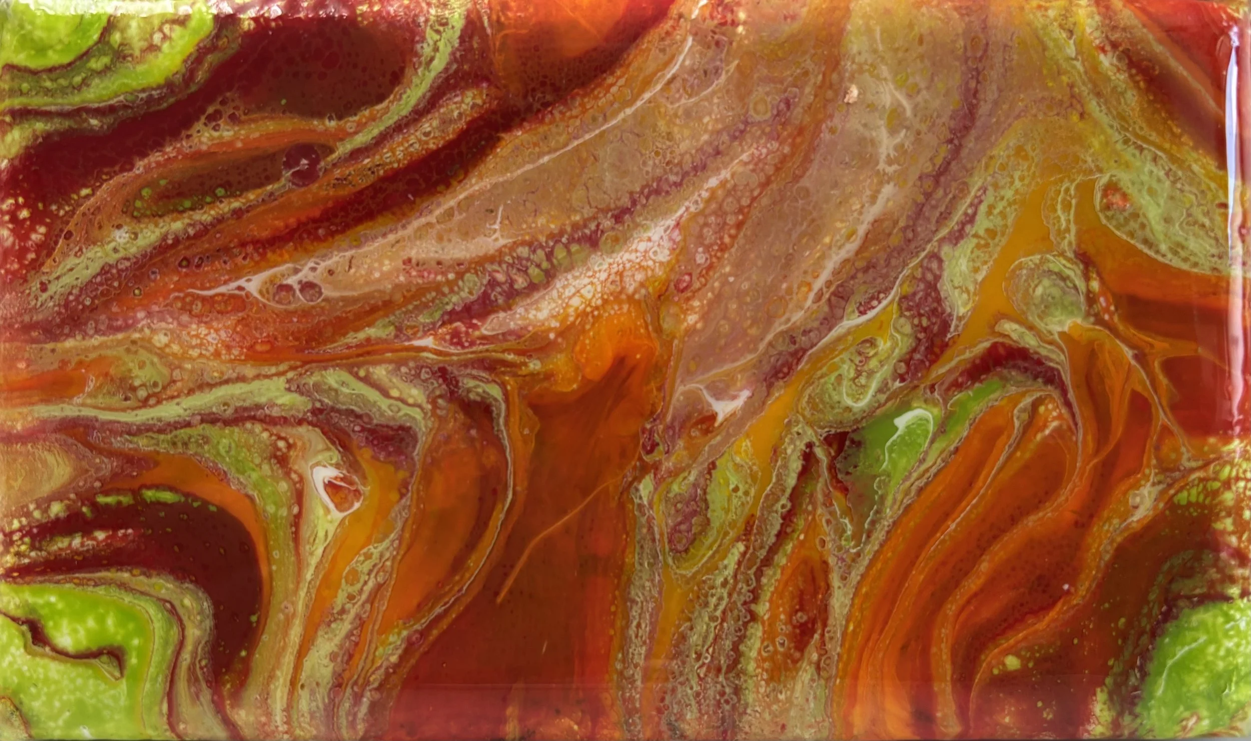 Close-up of colorful abstract marbled paint with swirls of red, yellow, green, and orange.