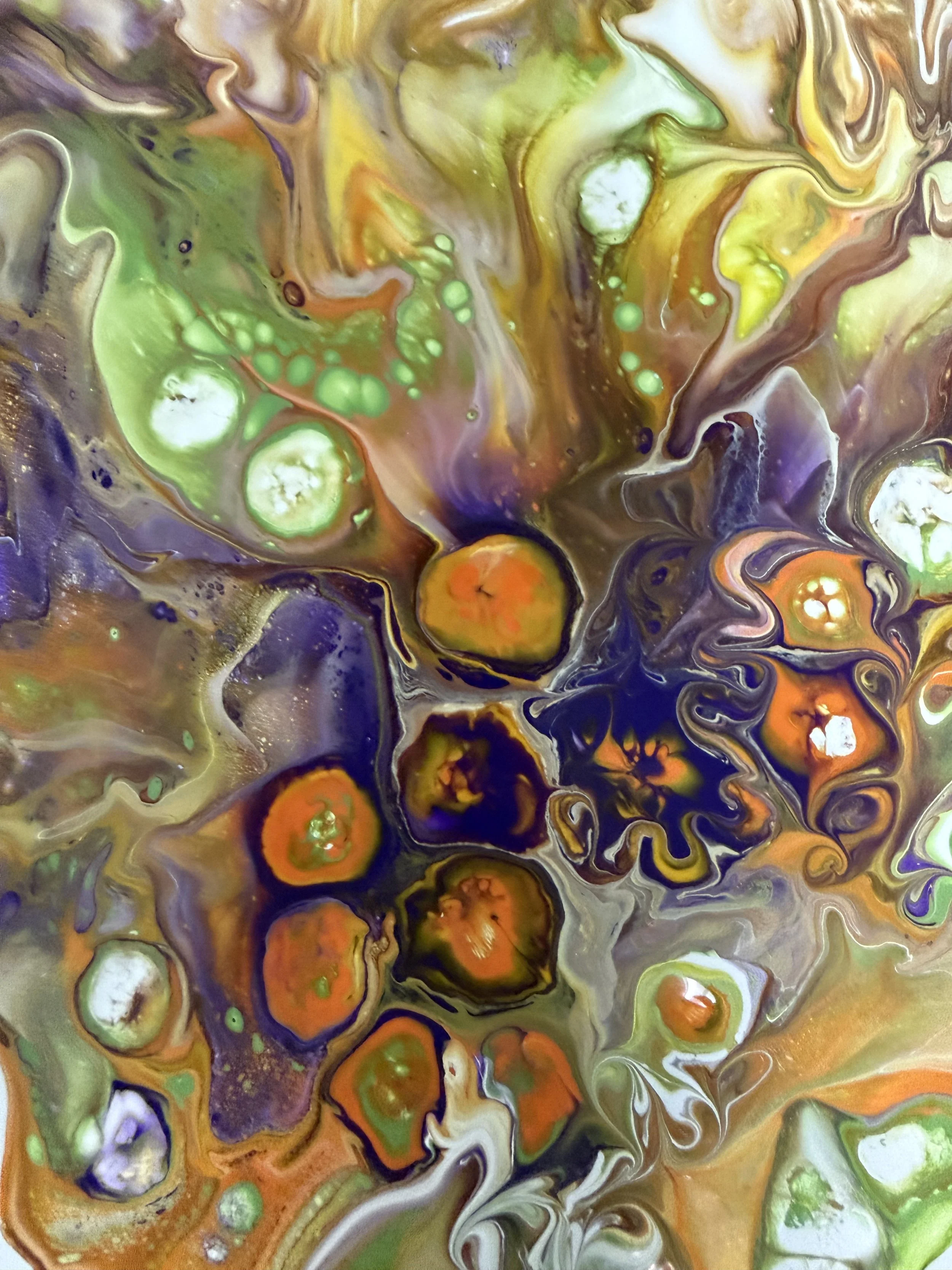 Abstract swirling mixture of green, orange, purple, white, brown, and black colors with various circular and irregular shapes.