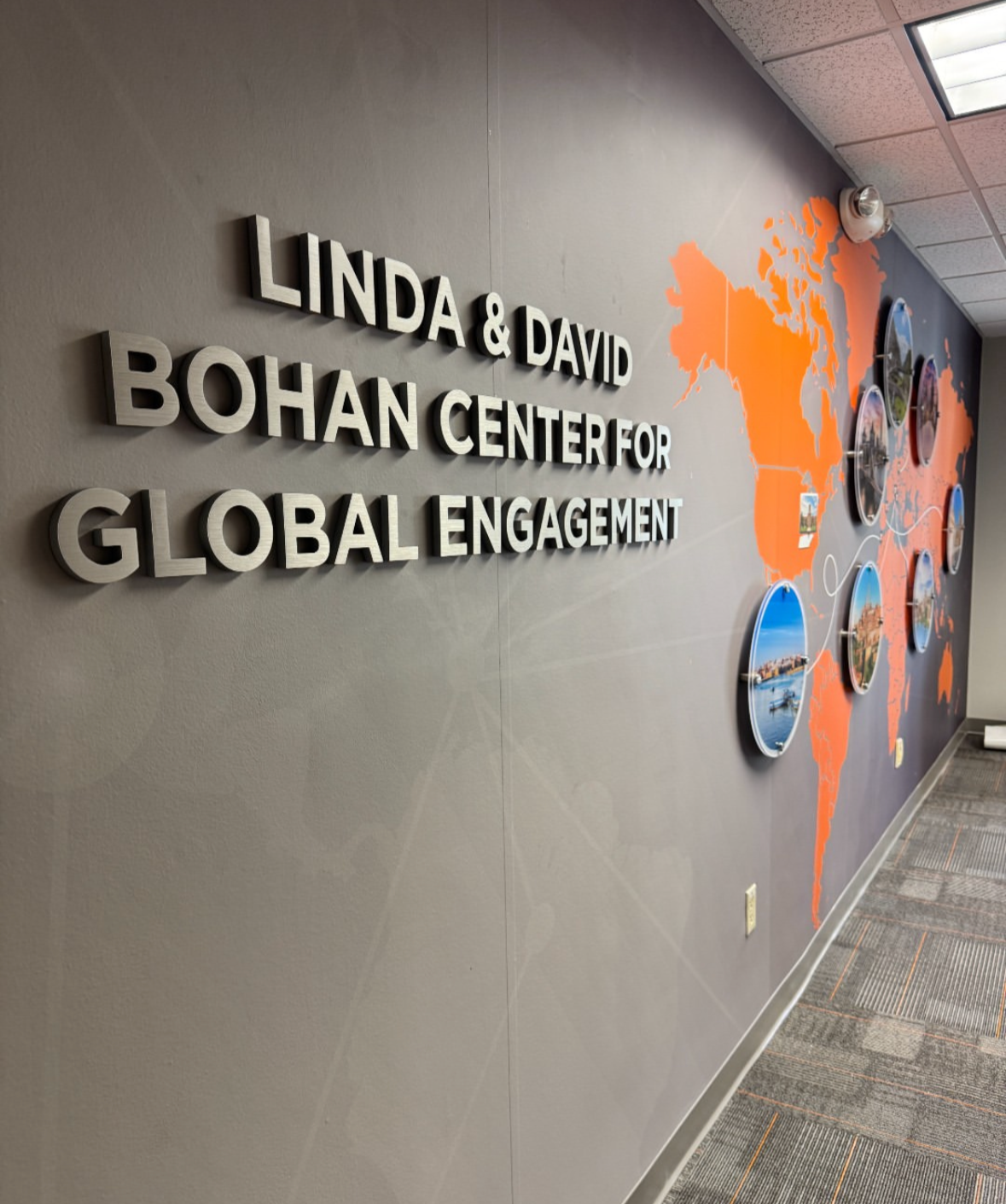 Wall display with the text 'Linda & David Bohan Center for Global Engagement' and a world map with connected photos of different locations.