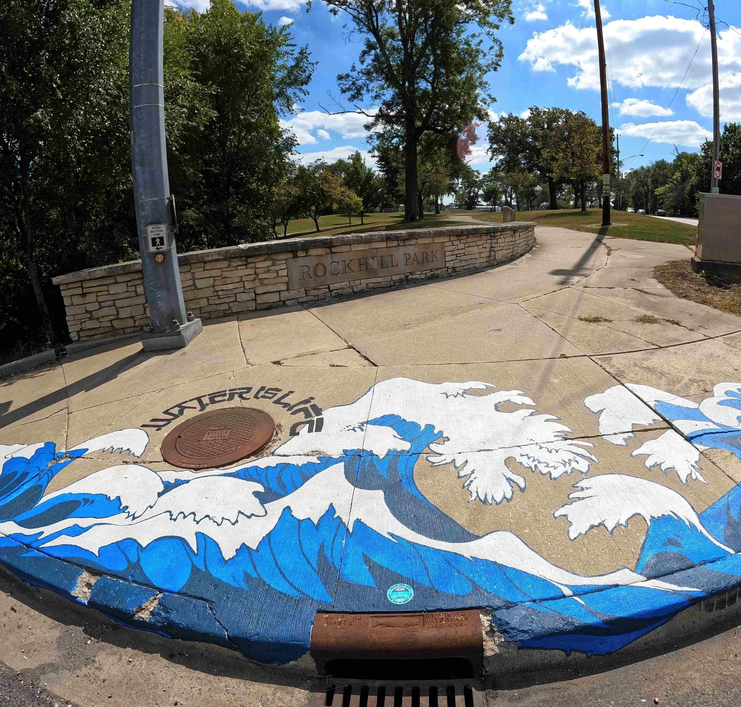Inspired by water, movement and the local natural landscape. The wave motif interacts with
the sidewalk and surrounding landscape, transforming a
functional surface into a dynamic visual experience. This mural was created as part of a public art prog