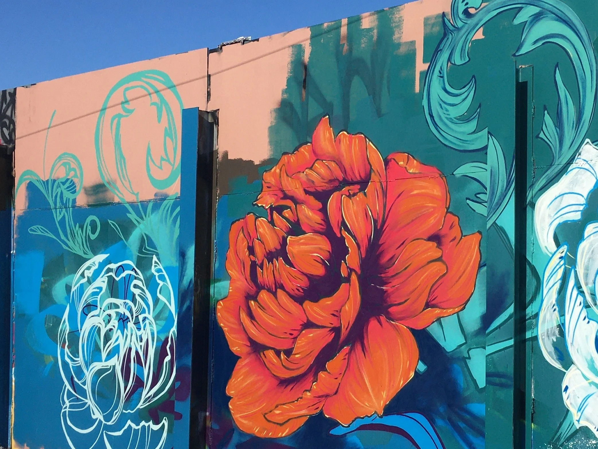 This graffiti jam production, hosted by Fort Wayne Open Walls, was created within an industrial setting, this mural juxtaposes organic floral forms against raw architectural surfaces. The composition adapts to structural interruptions, allowing the a