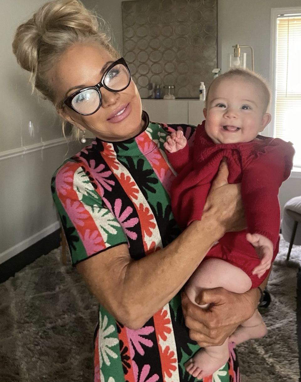 chiropractor in pink and green floral dress holding smiling baby