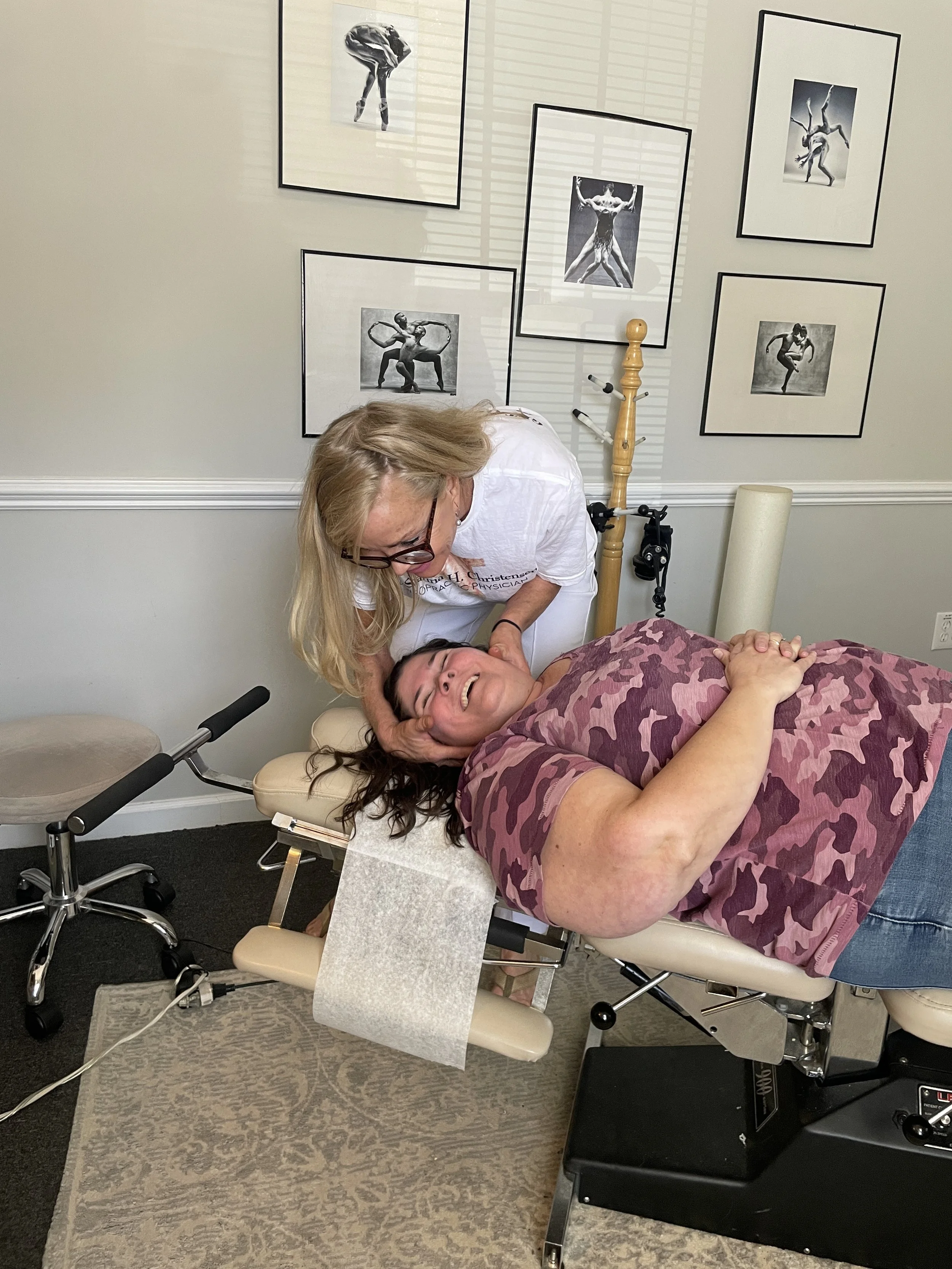 chiropractor and patient laughing  and talking while chiropractor adjusts patient's neck