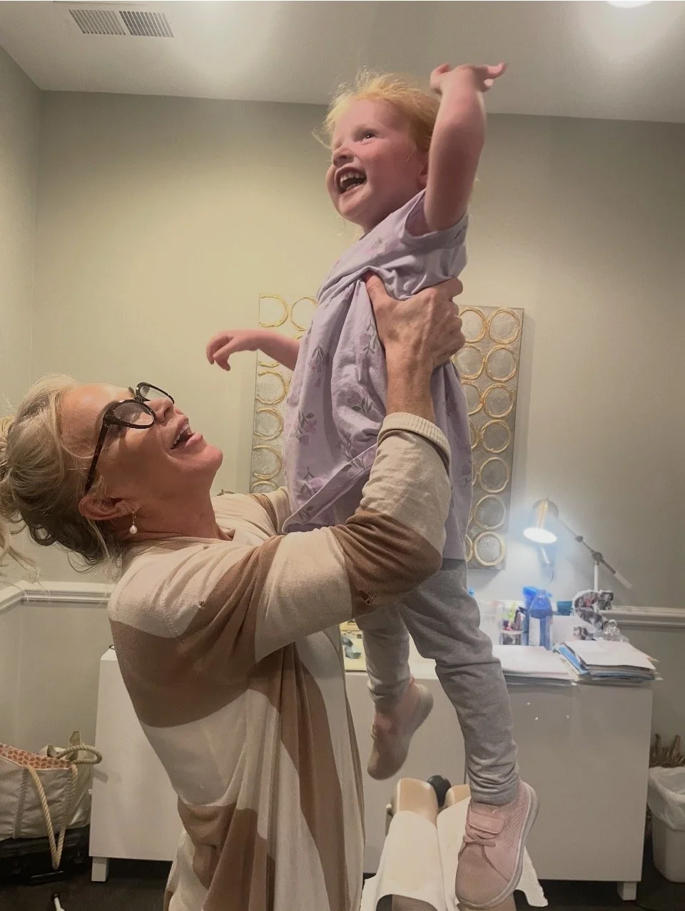 female chiropractor holds up small happy child.
