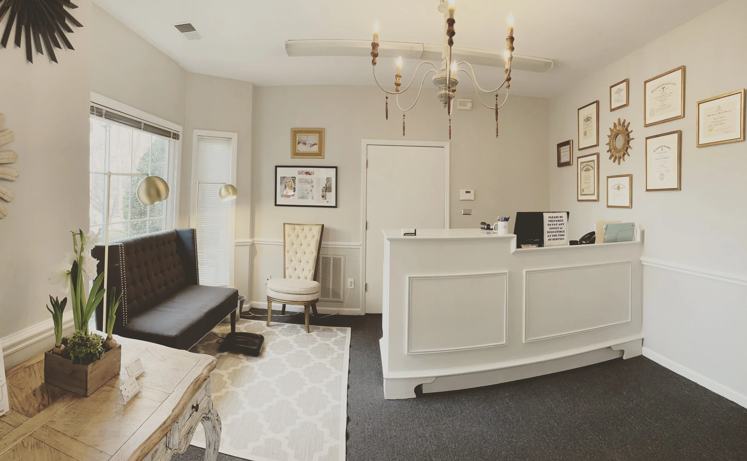 office lobby with large white desk and doctor's credentials on the wall