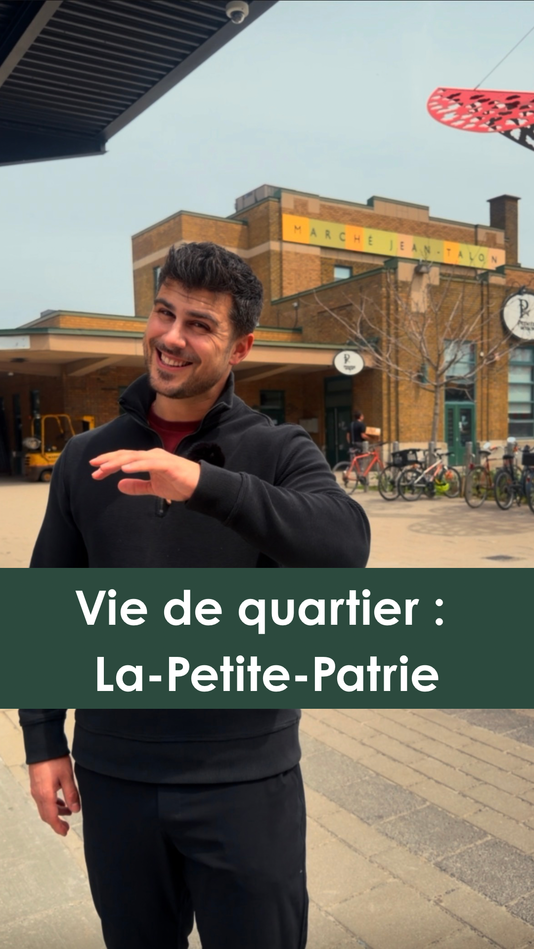 Un homme souriant qui se tient devant la place de Marché Jean-Talon dans le quartier La-Petite-Patrie, à Montréal, avec des vélos à l'arrière-plan et un bâtiment en briques.