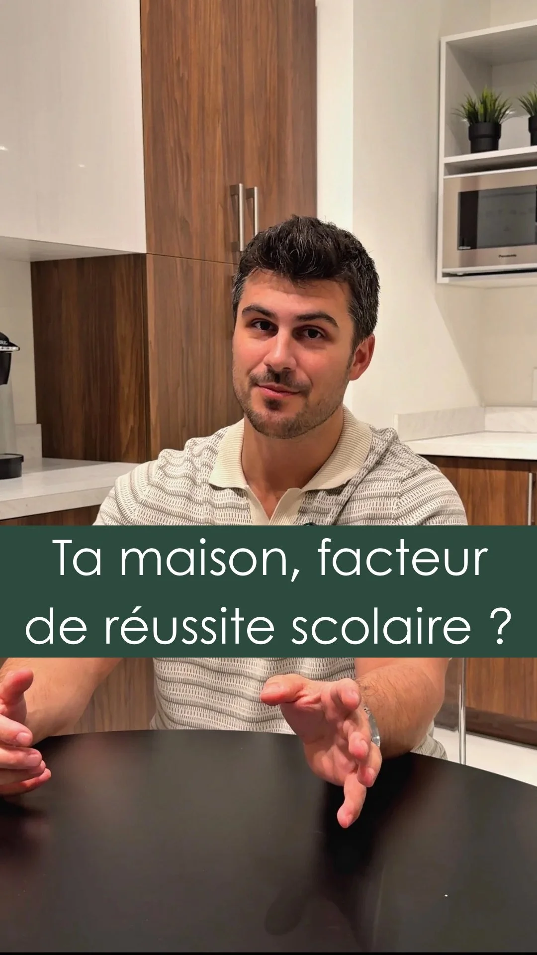 Un homme parle avec enthousiasme, assis à une table en cuisine, avec un texte en français superposé disant 'Ta maison, facteur de réussite scolaire ?'.
