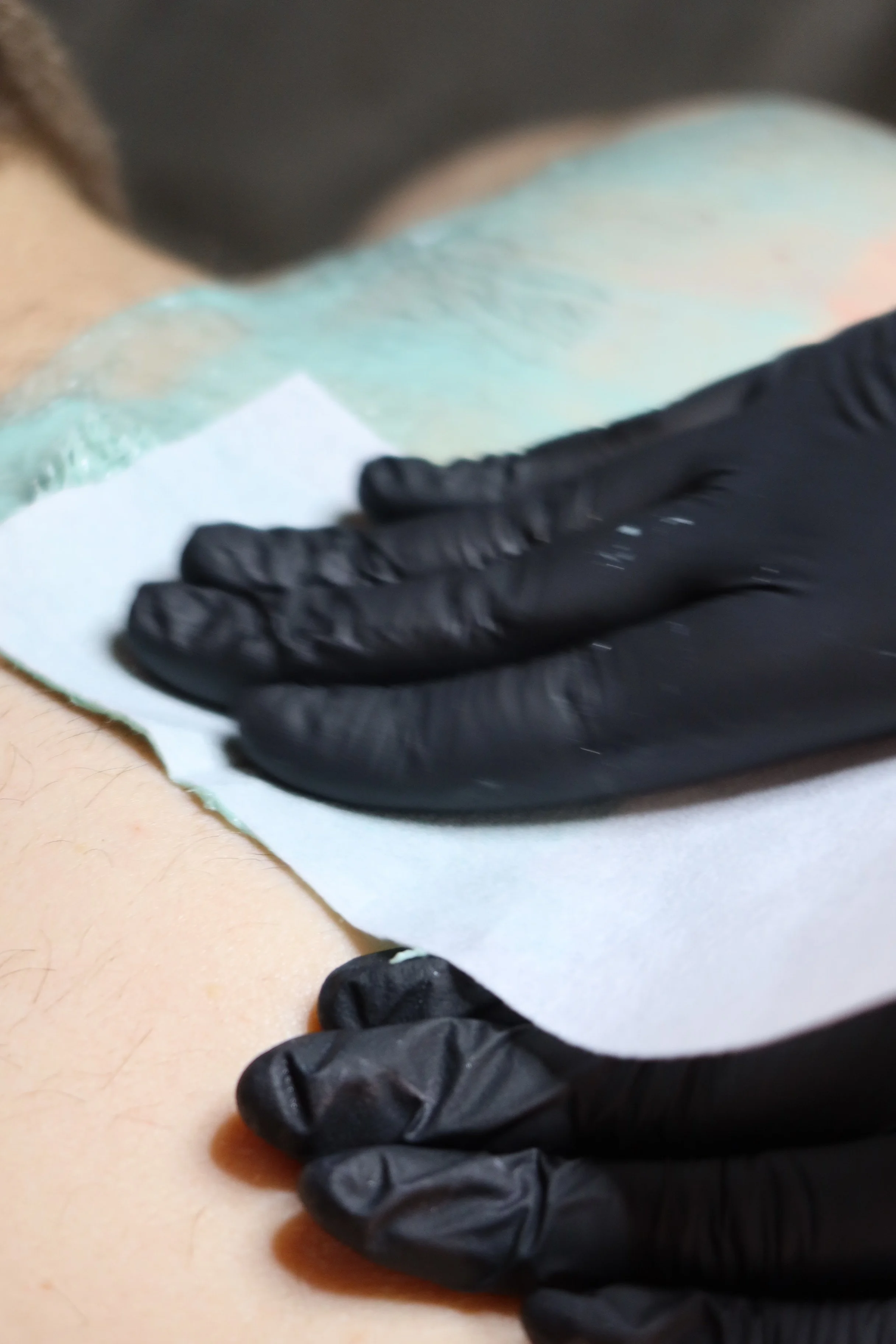 En person som får tatovering med hjelp av en utøver med svarte hansker.