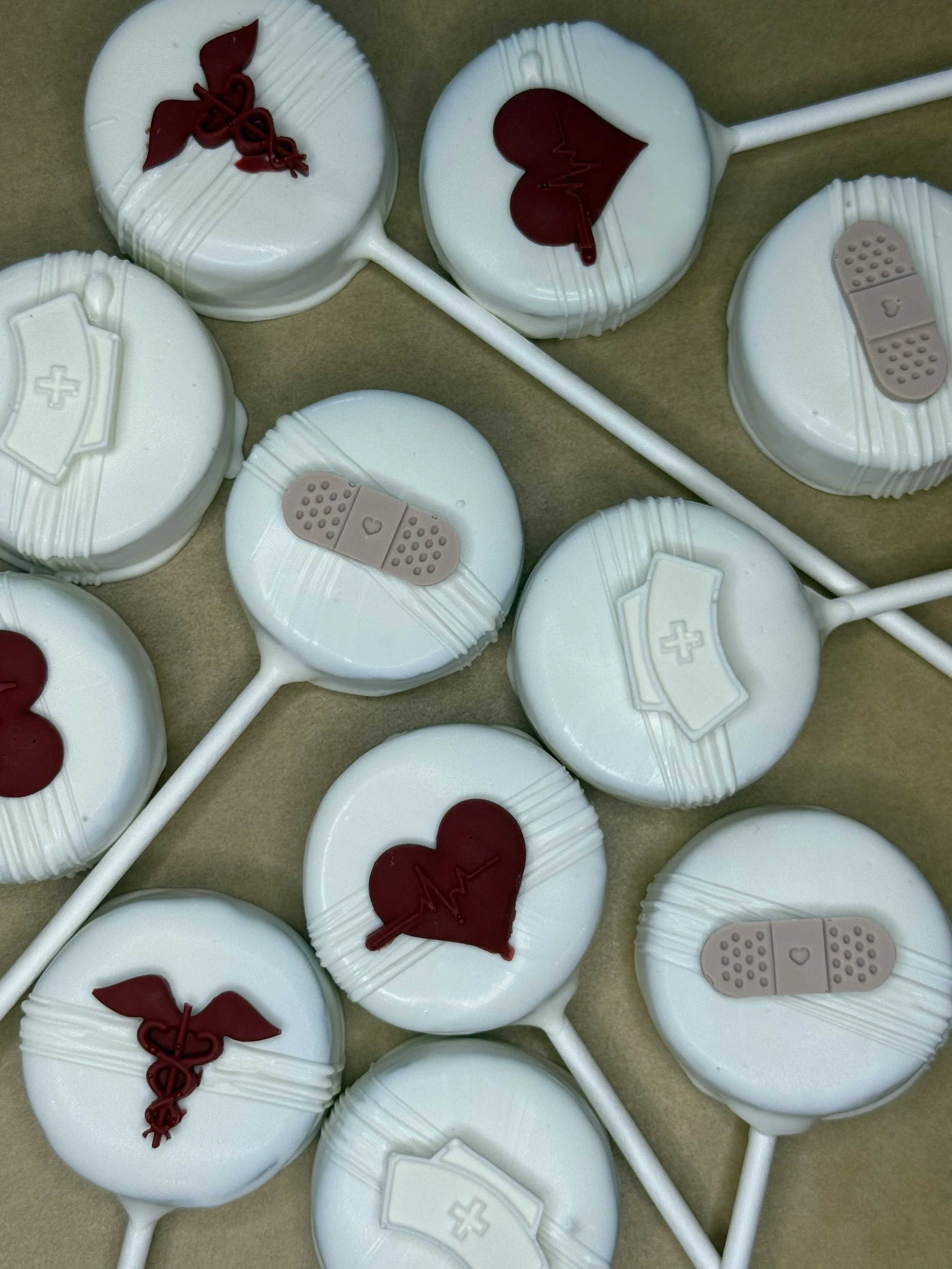 A collection of white lollipops with medical and health-related designs, including hearts with heartbeat lines, bandages, and medical crosses.