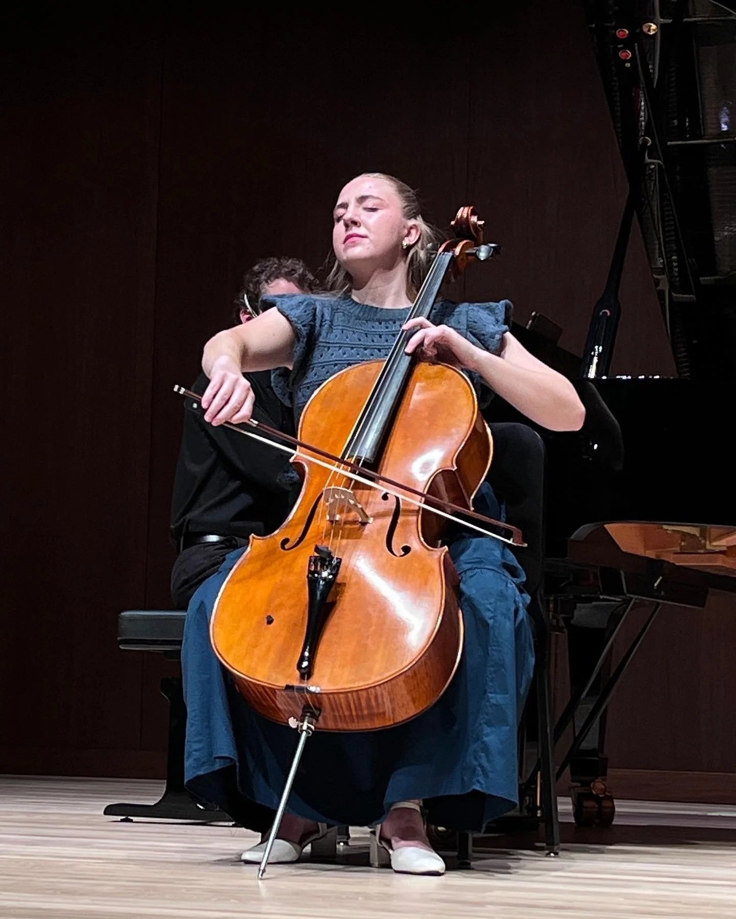 A woman playing a cello on stage during a performance.