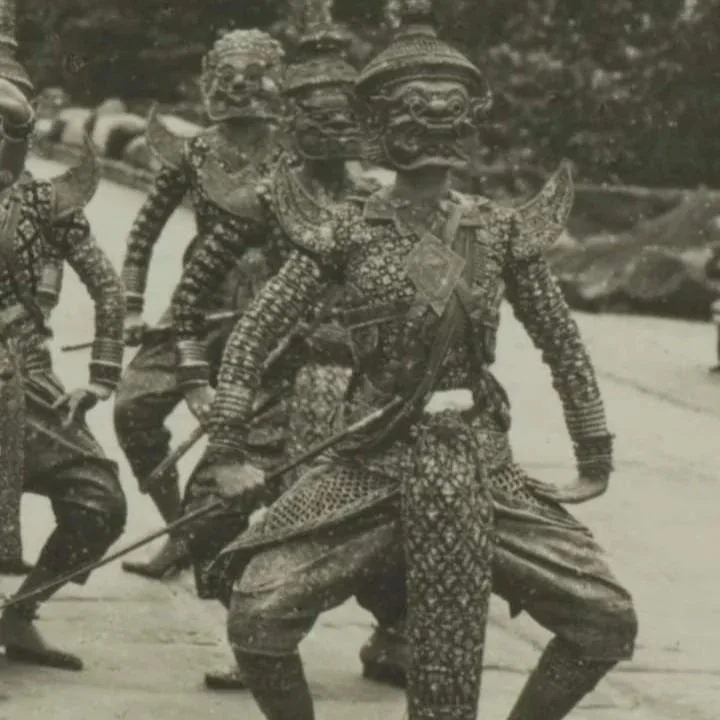 Historical photograph of a group of traditional dancers wearing ornate costumes and masks, performing in a parade or cultural event.