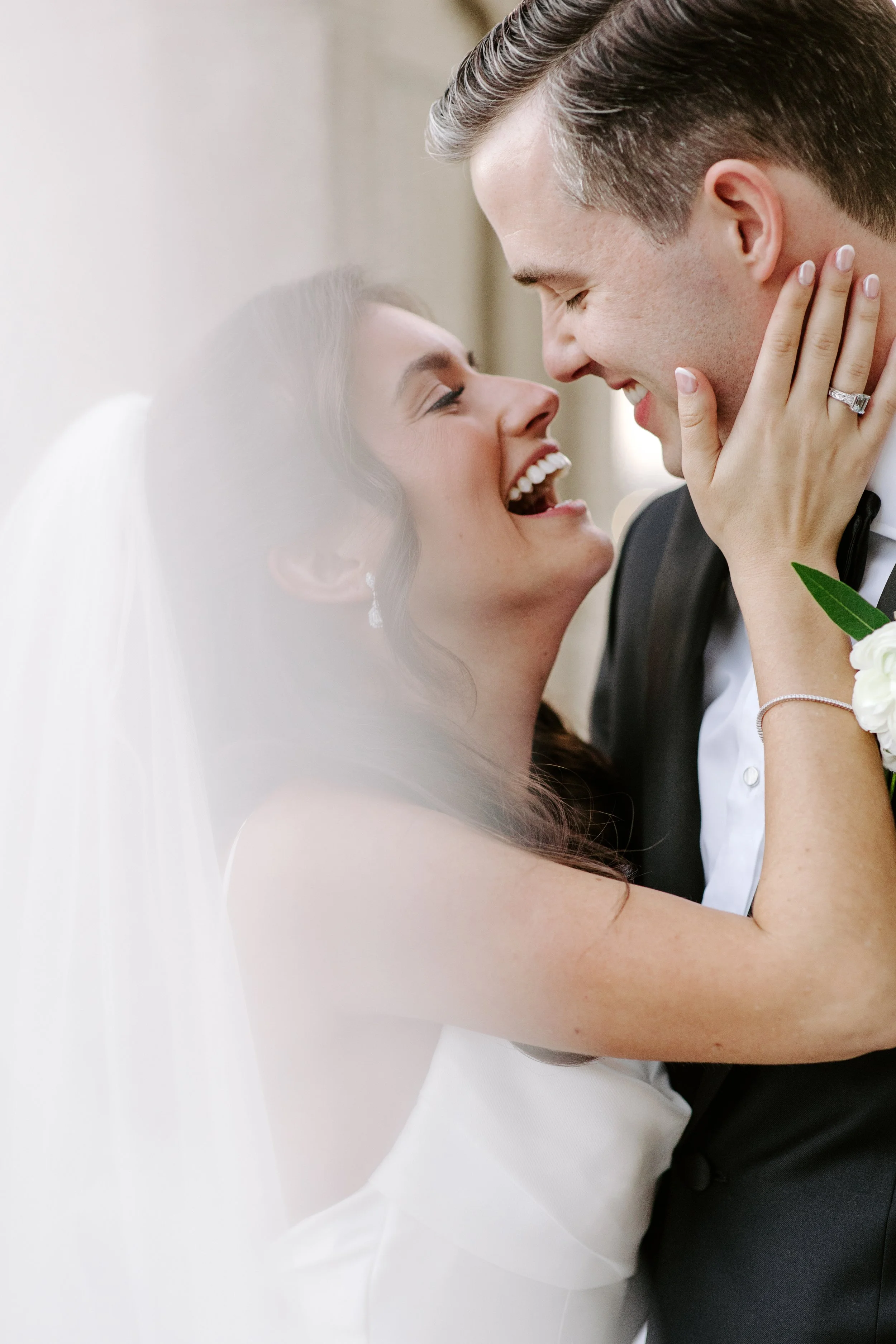 A bride and groom smiling and touching foreheads, closely embracing during a wedding celebration.