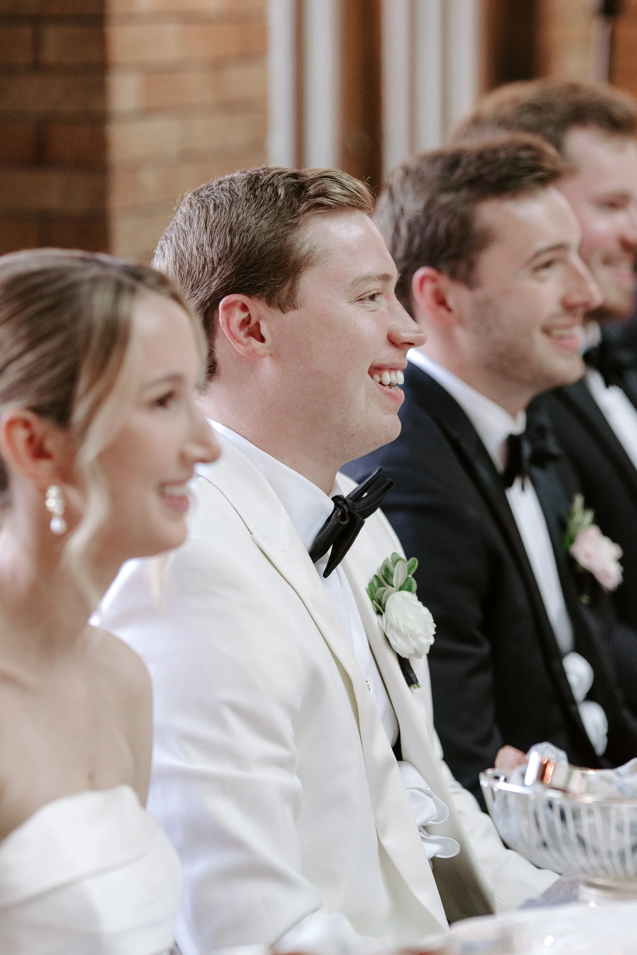 Group of people dressed in formal attire, seated at a table during a formal event, smiling and appearing happy.