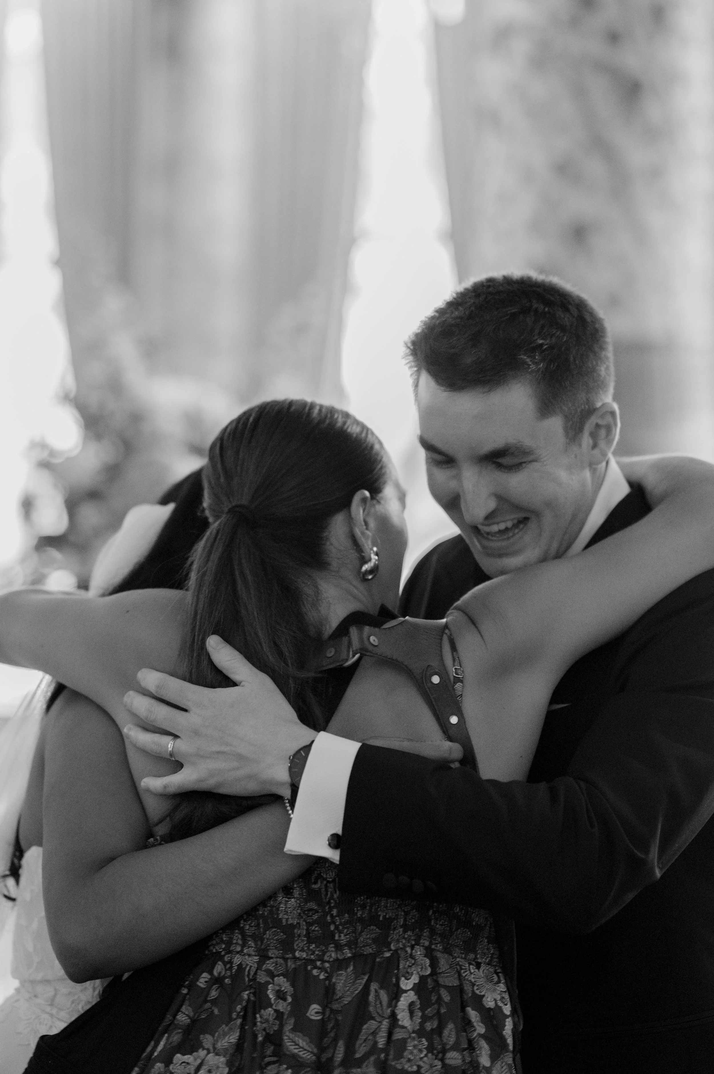 People hugging each other at a social event, smiling and showing affection.