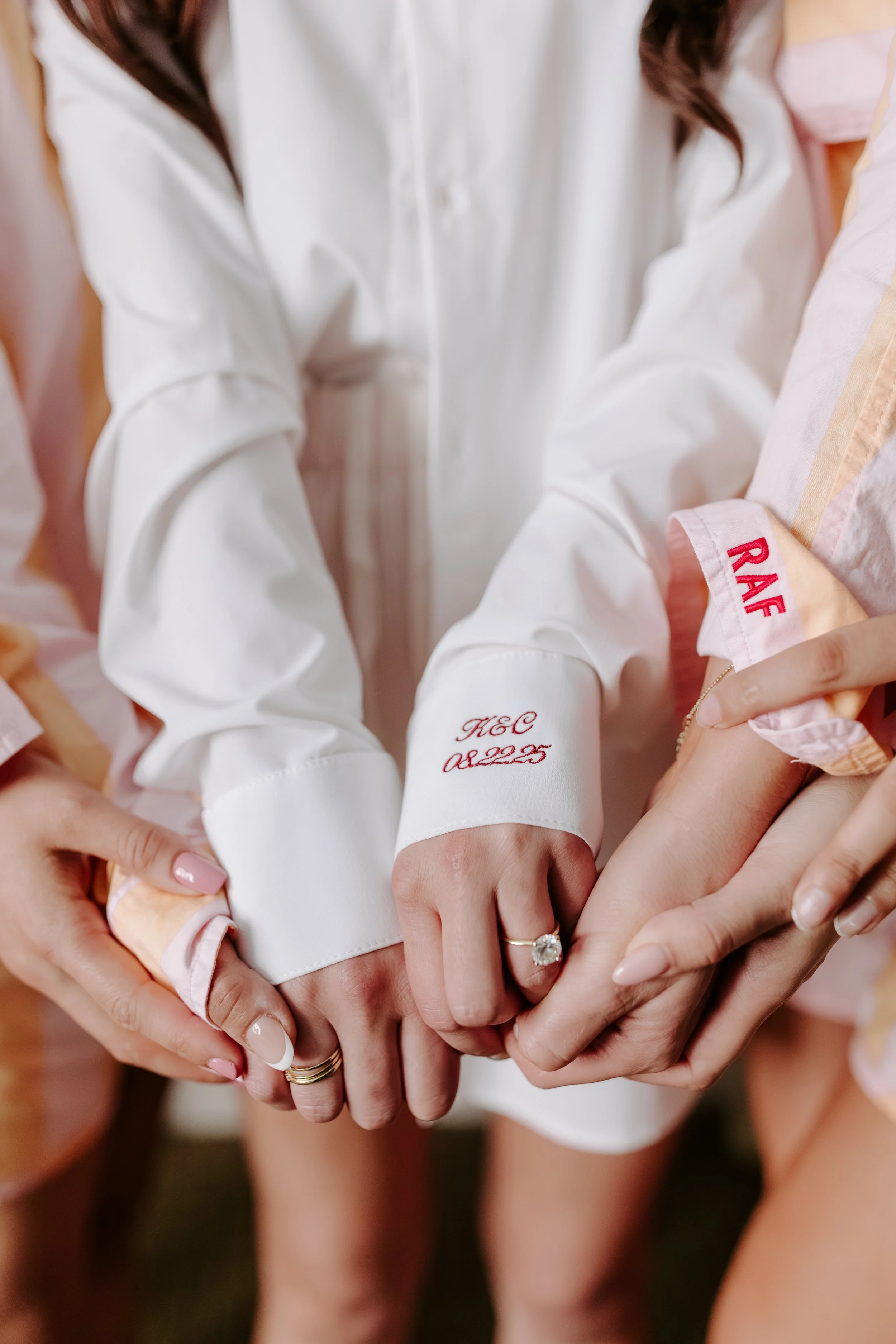 Close-up of multiple hands, including an adult's and a child's, intertwined in a gesture of unity and support, with a ring on one finger.