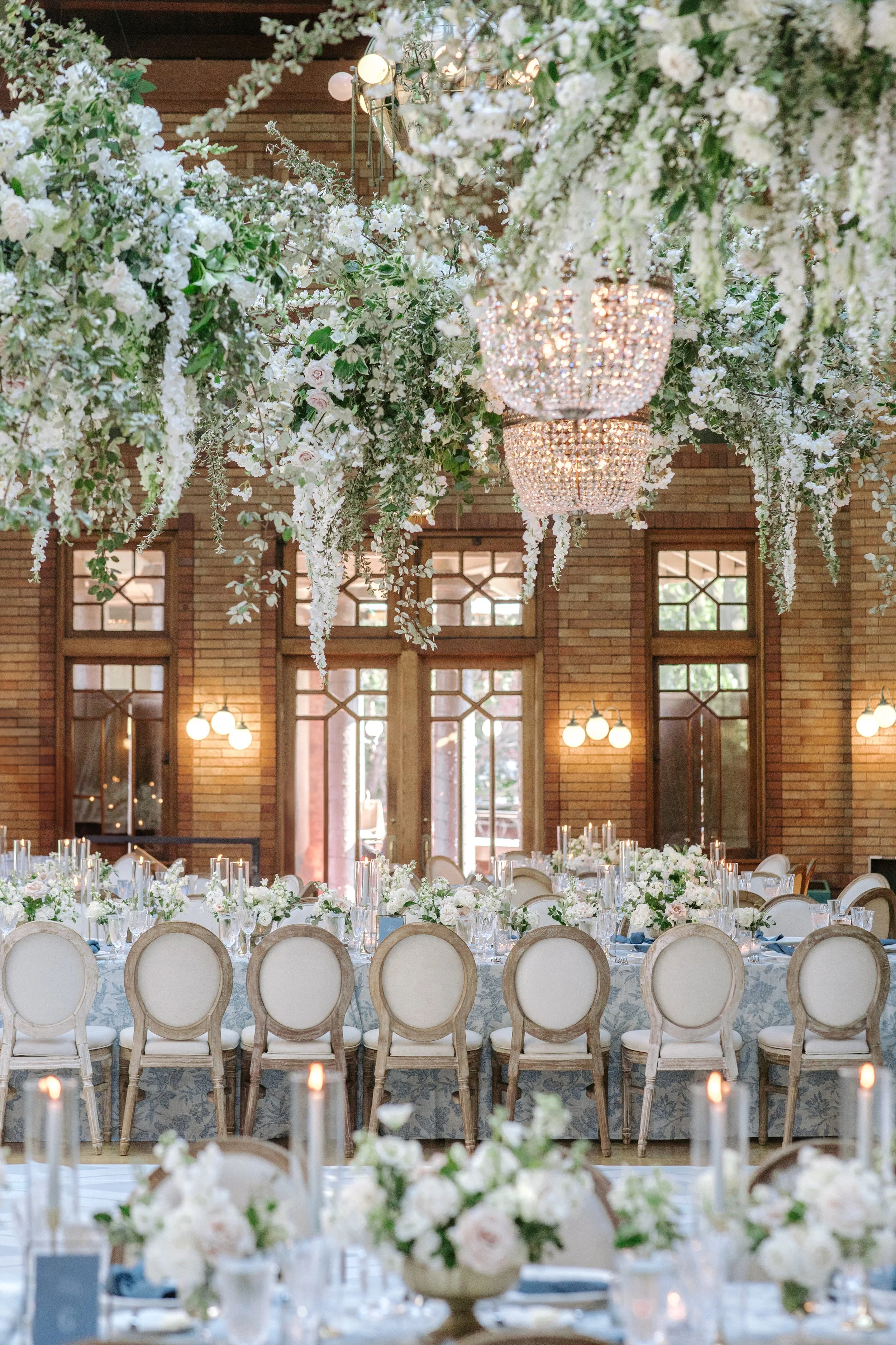 Elegant event space decorated with cascading white flowers and chandeliers for a formal gathering or wedding reception.